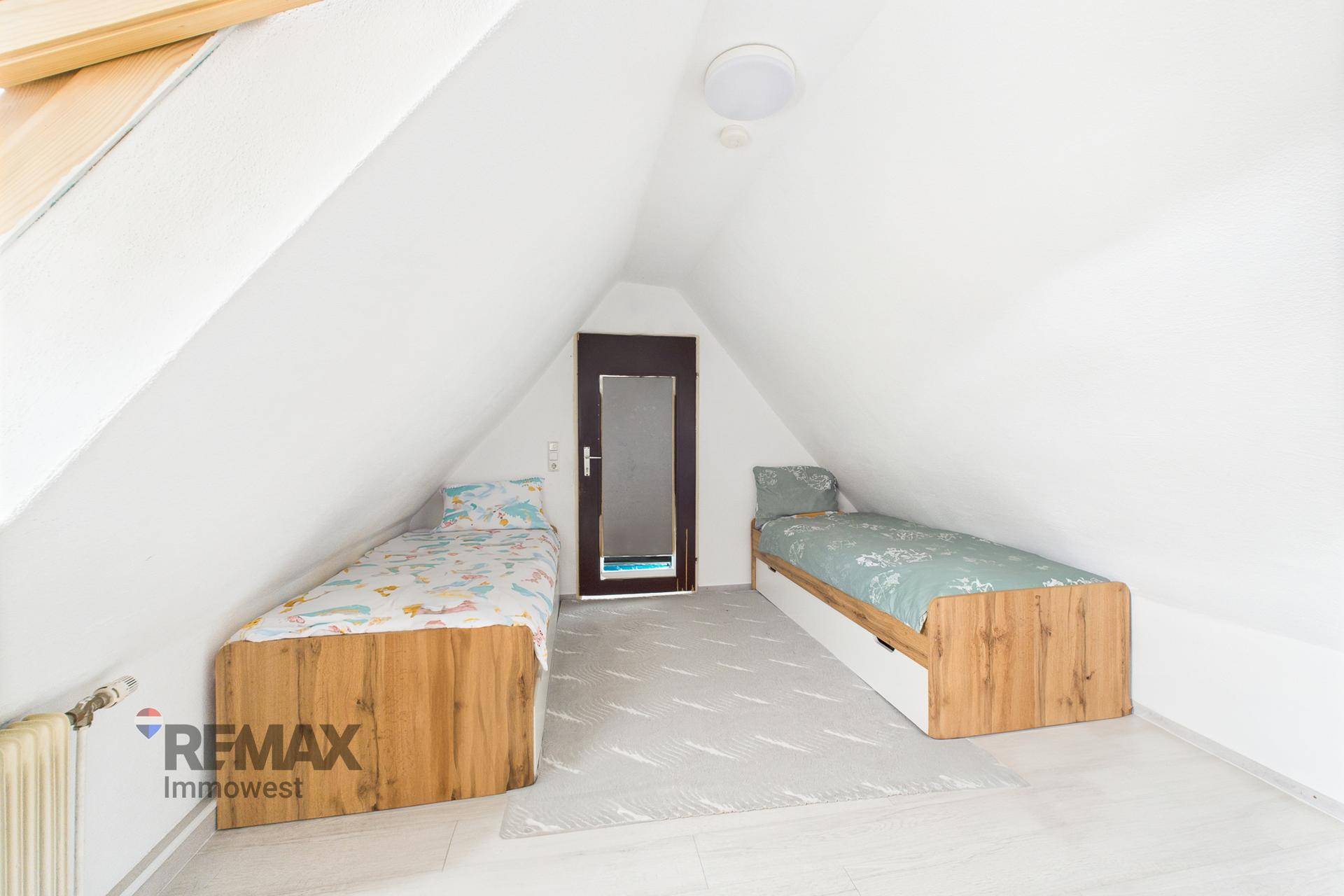 Kinderzimmer im Dachgeschoss mit zwei Einzelbetten und Dachfenster.