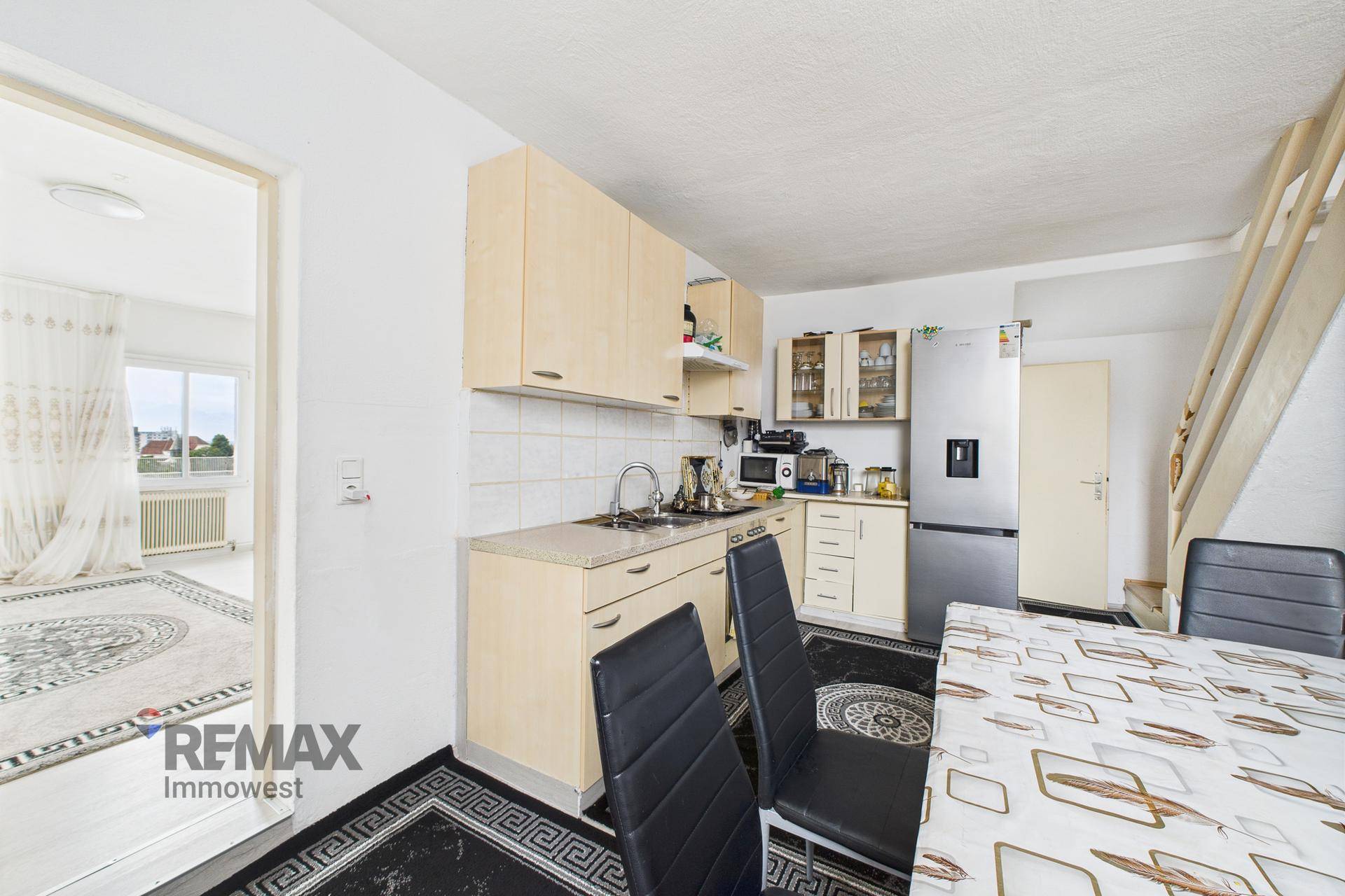 Funktionale Küche mit hellen Holzschränken, Essbereich und Blick in den Wohnraum.