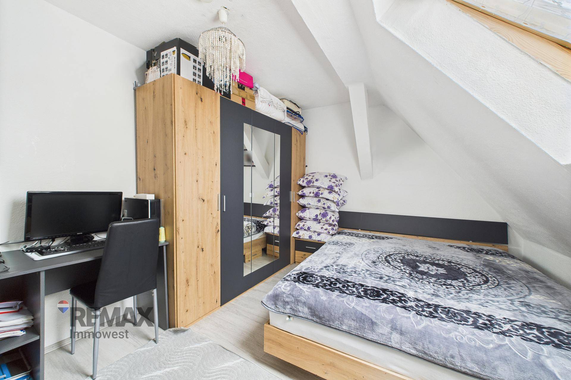 Schlafzimmer im Dachgeschoss mit Bett, Kleiderschrank und Schreibtisch.