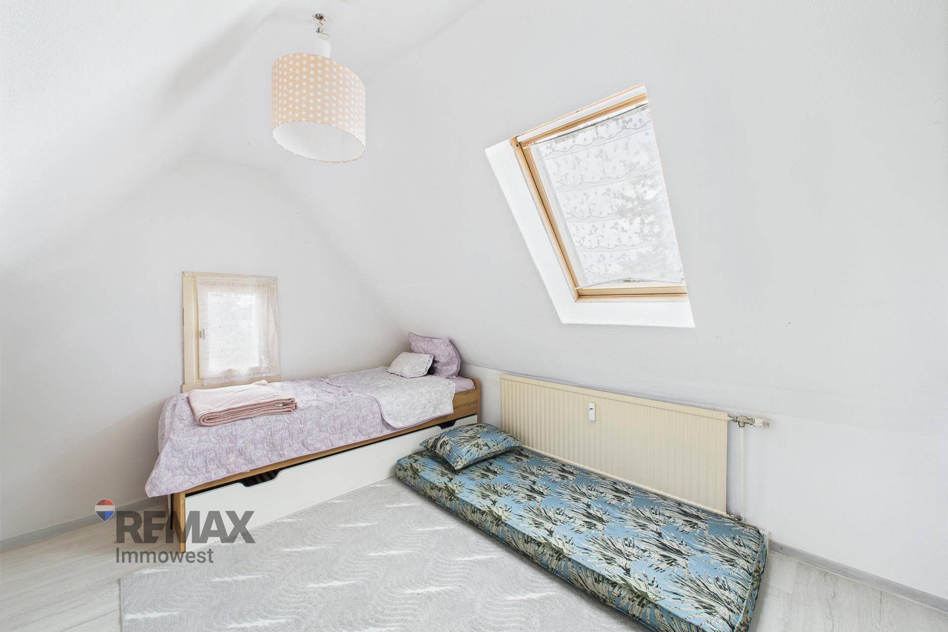 Gemütliches Schlafzimmer im Dachgeschoss mit Einzelbett und Dachfenster.