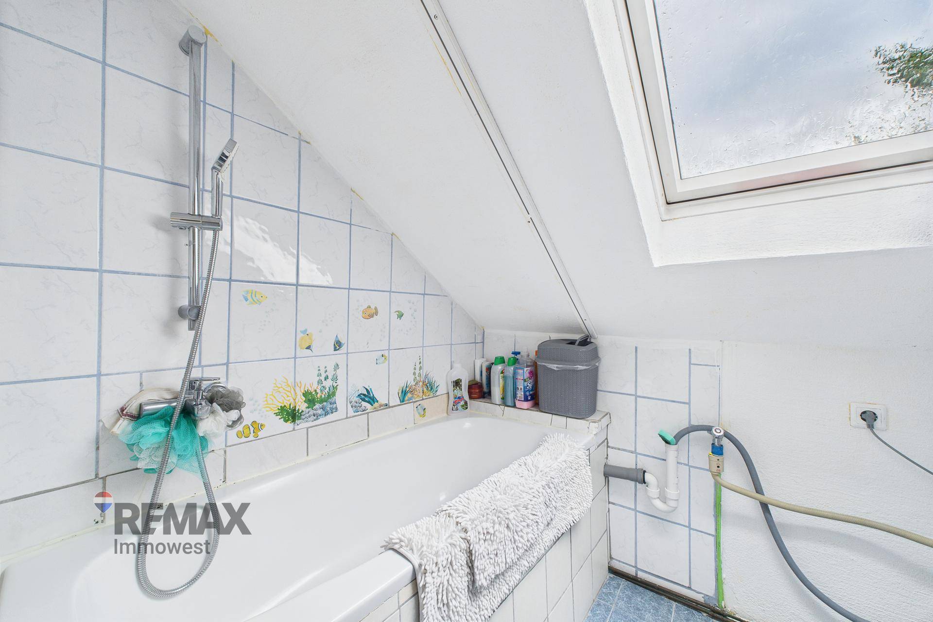 Badezimmer im Dachgeschoss mit Badewanne, Fliesen und Dachfenster.