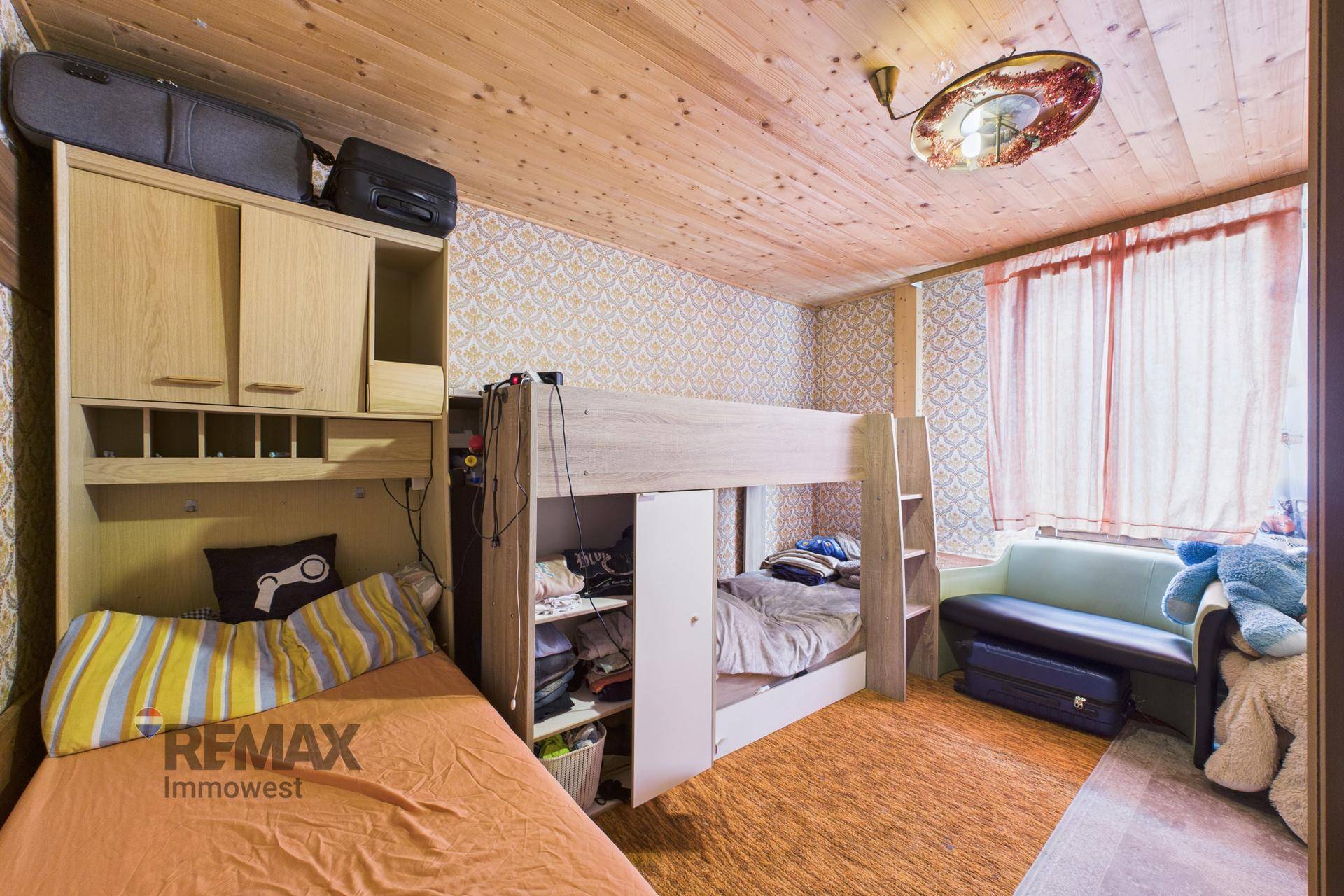 Gemütliches Schlafzimmer mit Etagenbett, Einzelbett und Holzdecke, ideal für Kinder.