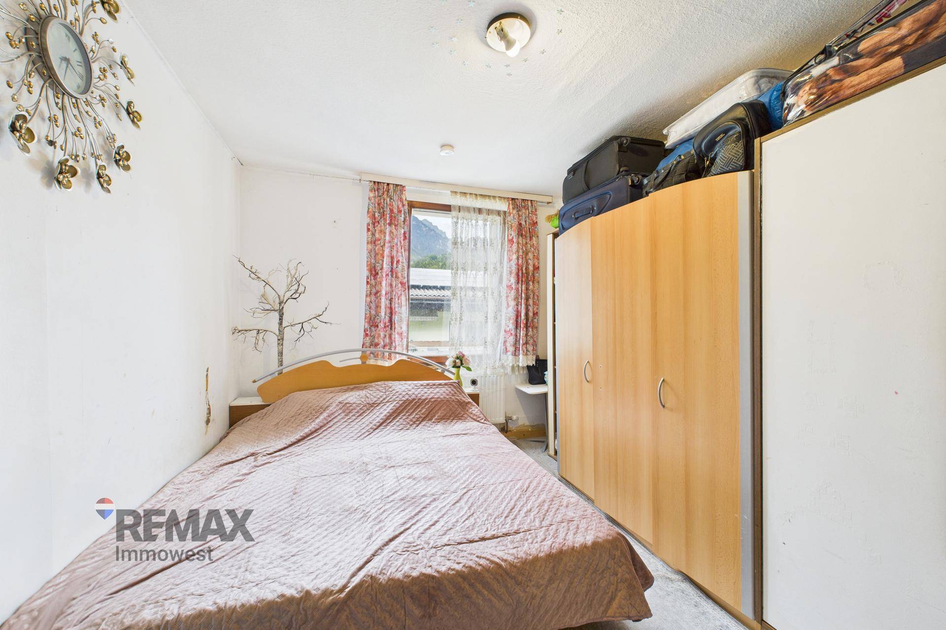 Schlafzimmer mit Doppelbett, Kleiderschrank und Fenster mit Blick nach draußen.
