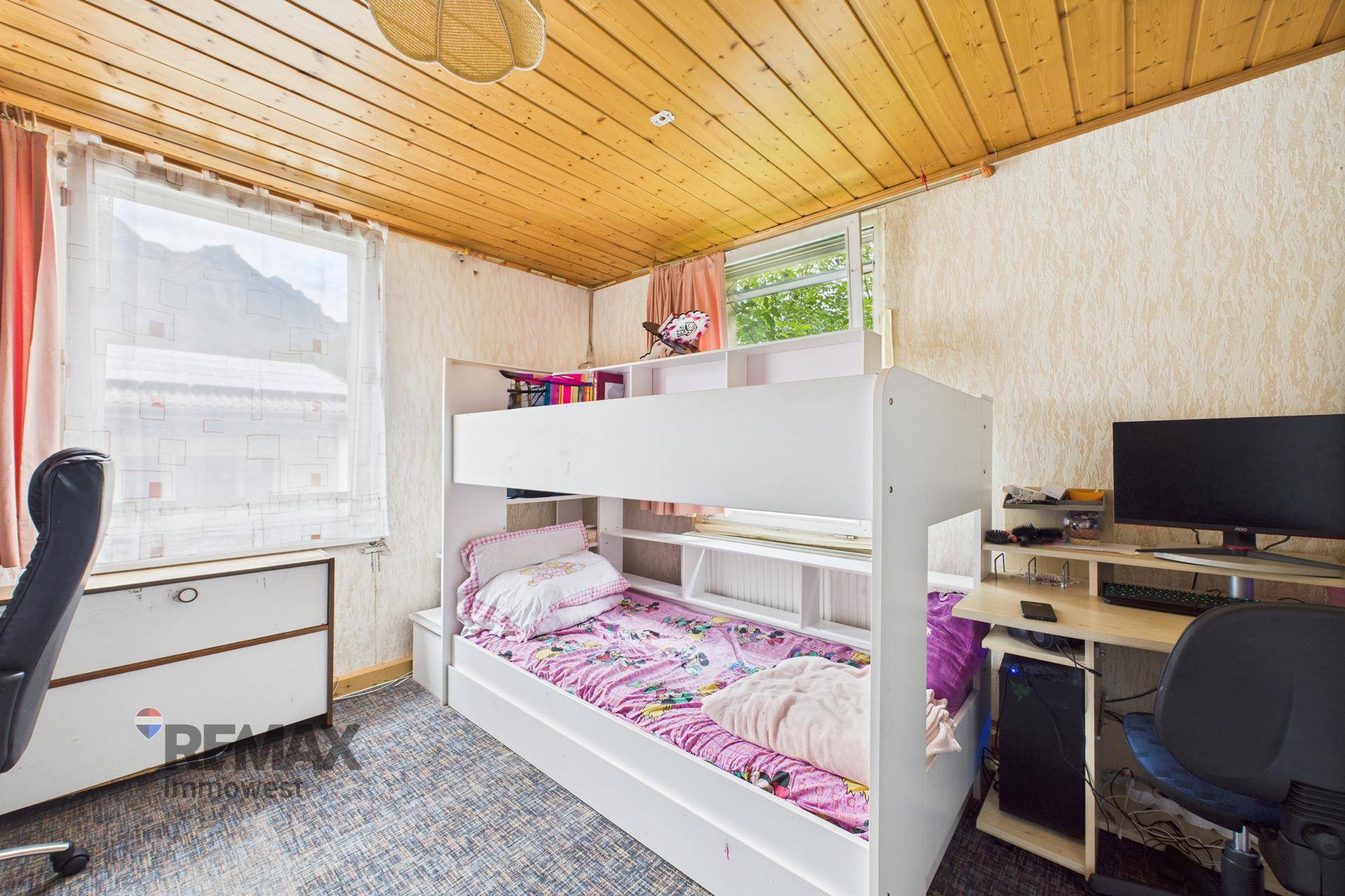 Helles Kinderzimmer mit Etagenbett, Schreibtisch und Holzdecke, ideal für junge Bewohner.
