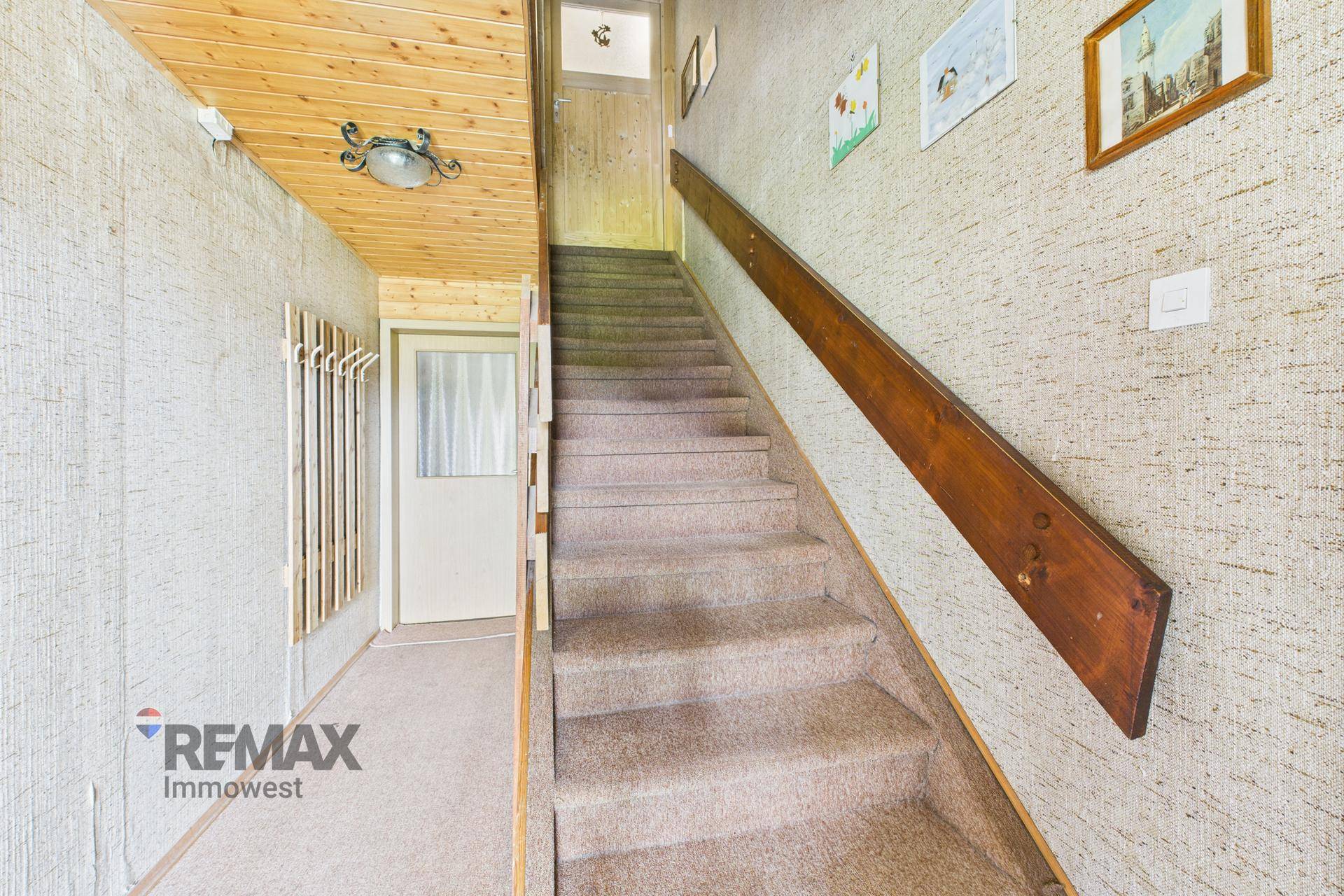 Flur mit Teppichboden, Holzdecke und Holztreppe, die in die oberen Stockwerke führt.