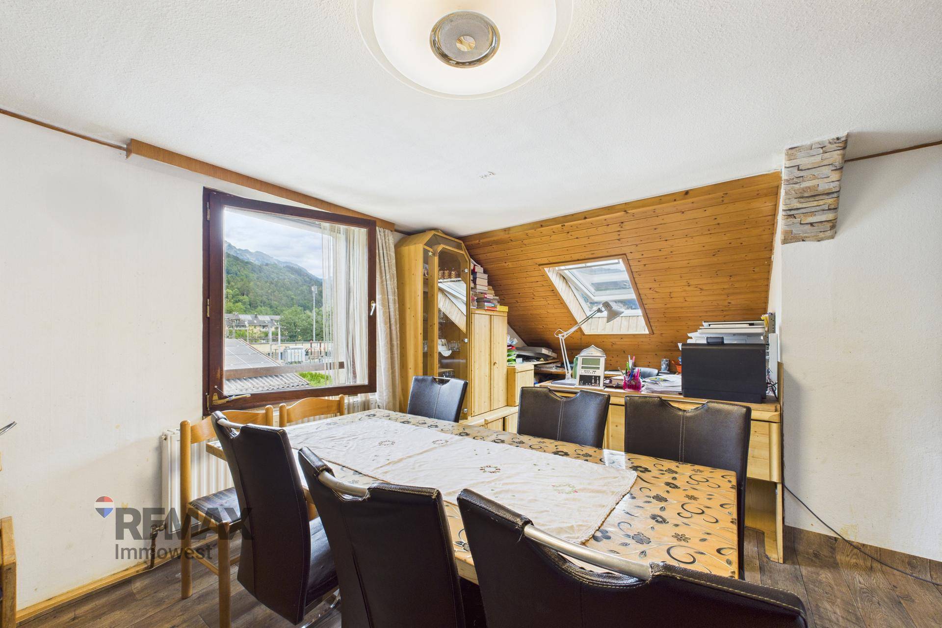 Esszimmer mit großem Esstisch, Stühlen und Dachfenstern für natürliches Licht.