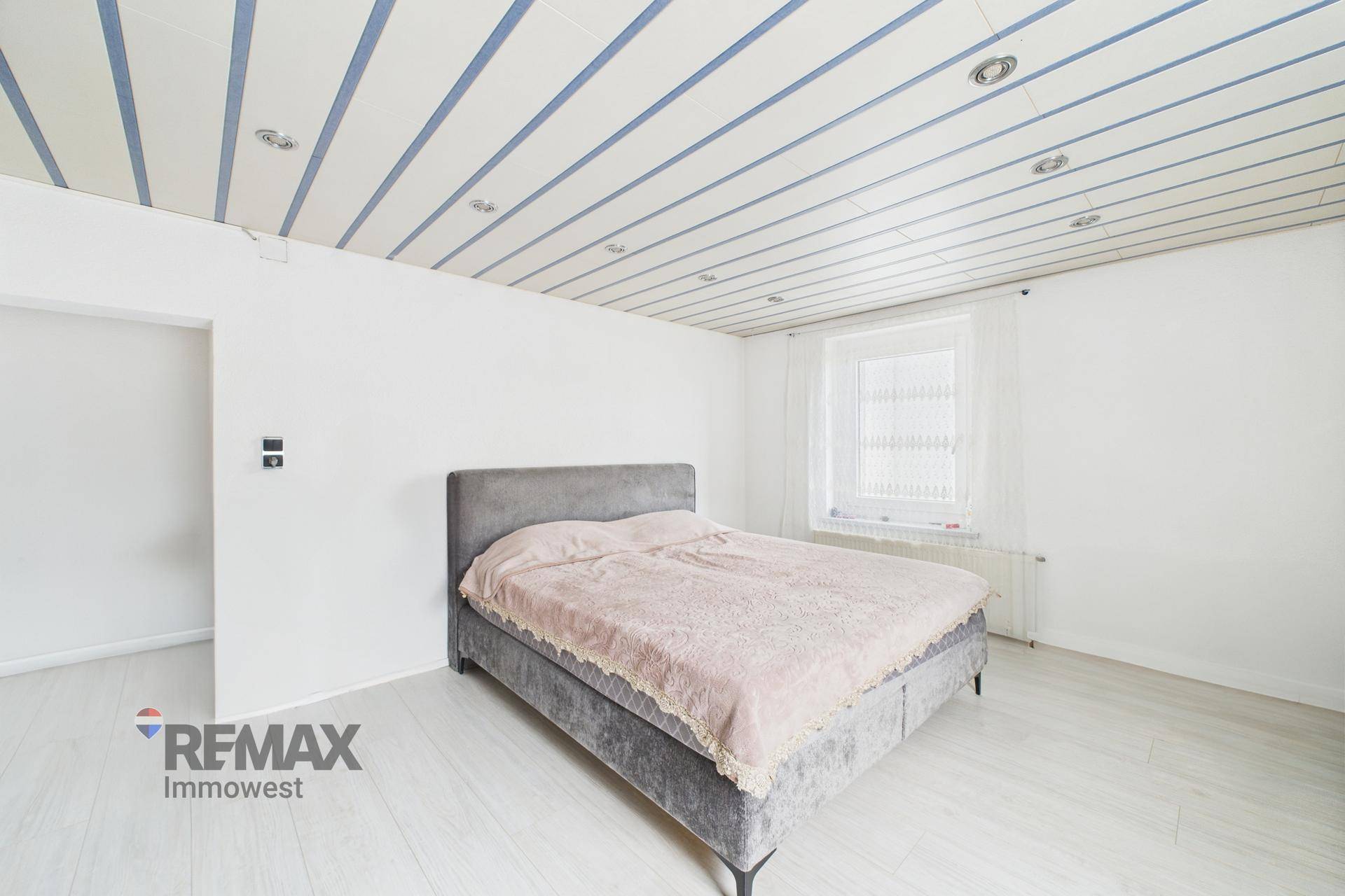 Schlafzimmer mit Doppelbett, hellem Holzboden und weiß gestrichenen Wänden.