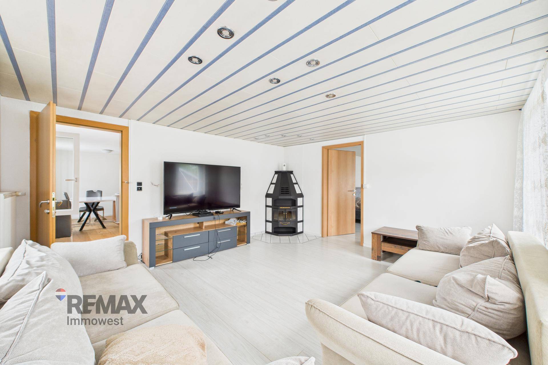 Gemütliches Wohnzimmer mit Kaminofen, Fernseher und bequemen Sofas.