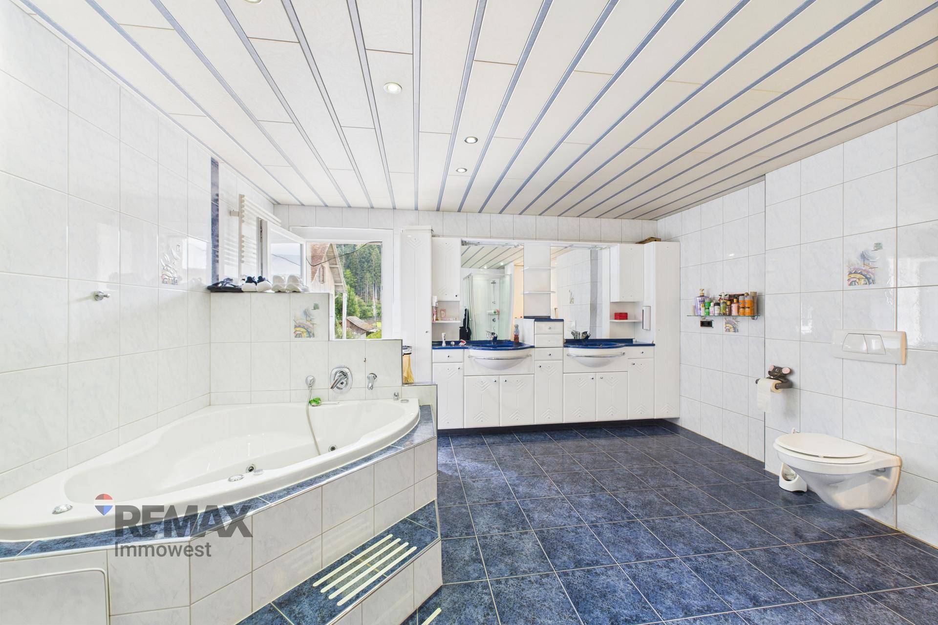 Großes Badezimmer mit Whirlpool-Badewanne, Doppelwaschbecken und blauen Fliesen.