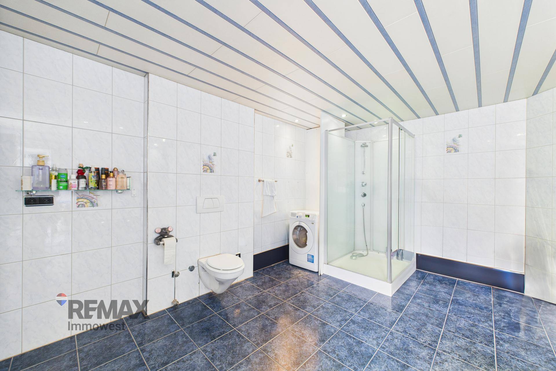 Geräumiges Badezimmer mit Duschkabine, WC und Waschmaschine.