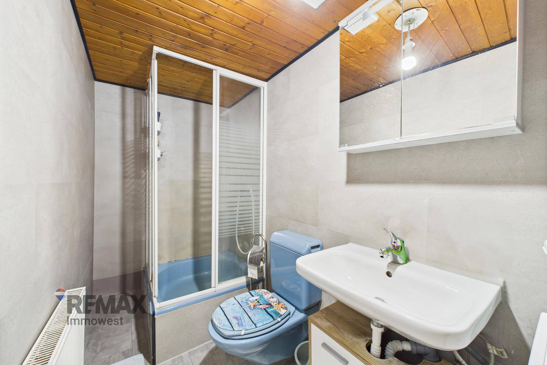 Kleines Badezimmer mit Dusche, WC und Holzdecke.