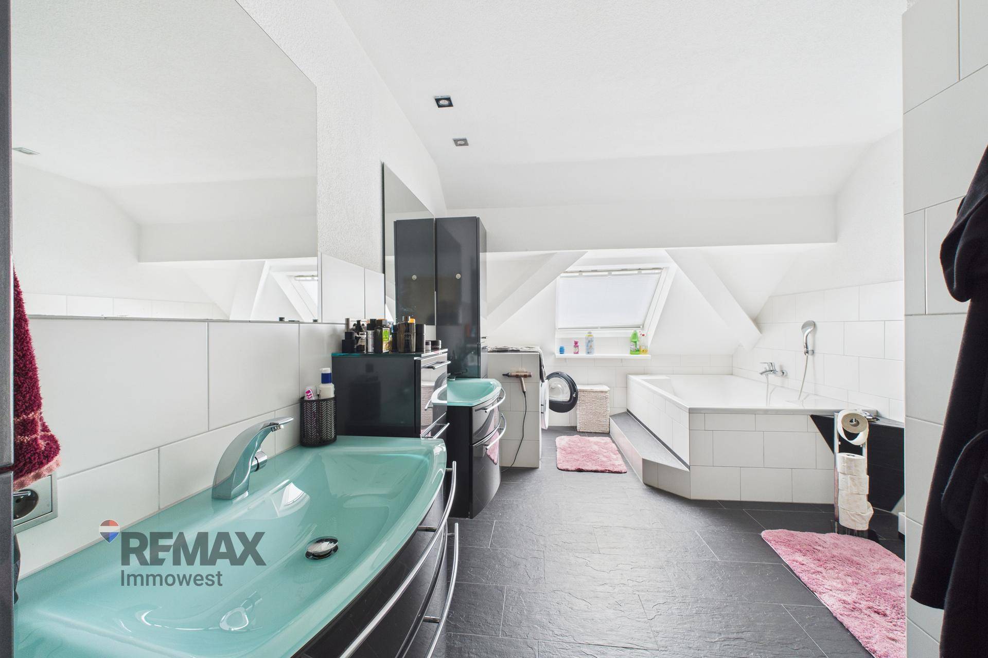 Geräumiges Badezimmer mit mintgrünem Waschbecken, Badewanne und Dachfenster.