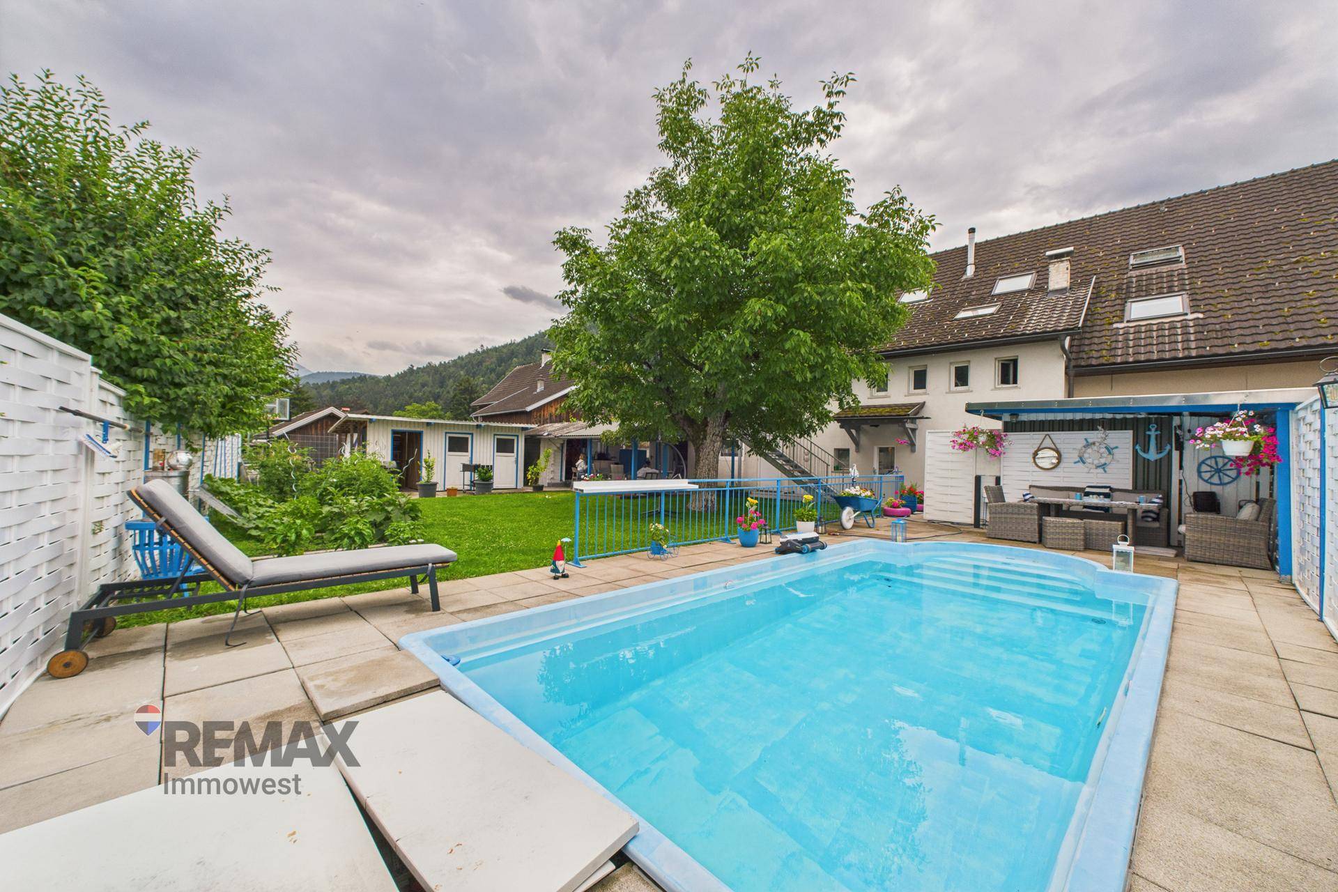 Großer Garten mit Swimmingpool, Liegestühlen und überdachtem Sitzbereich im Freien.