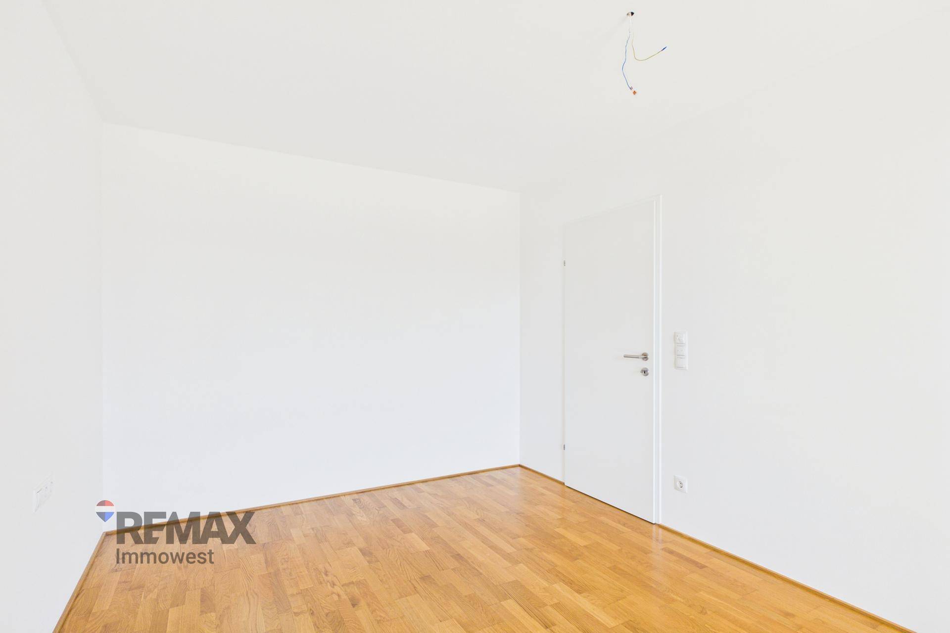 Leeres Zimmer mit hellem Holzboden und weiß gestrichenen Wänden, bereit zur individuellen Gestaltung.