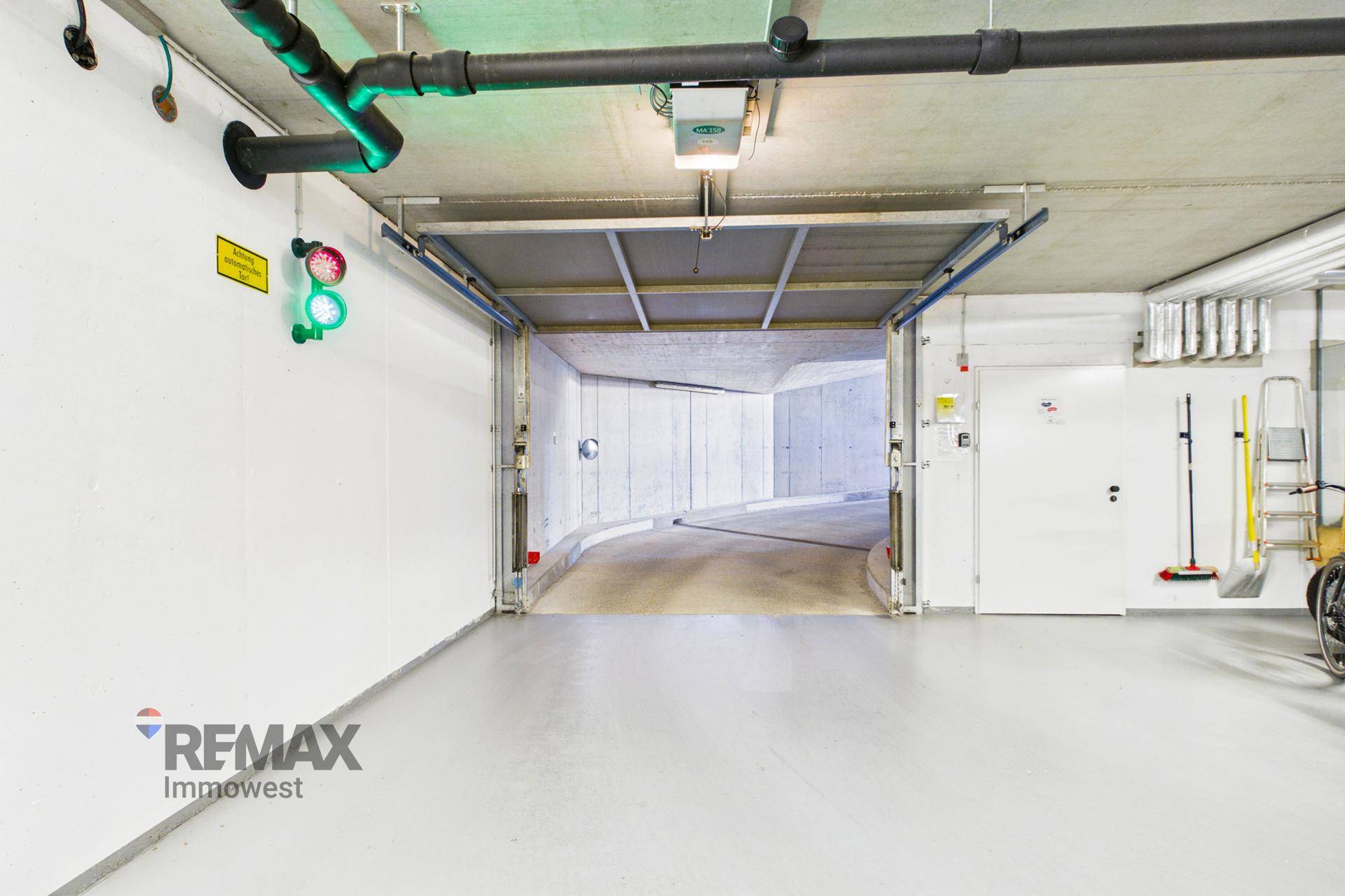 Einfahrt zur Tiefgarage mit geöffnetem Tor und Rampe, die in den Untergrund führt.