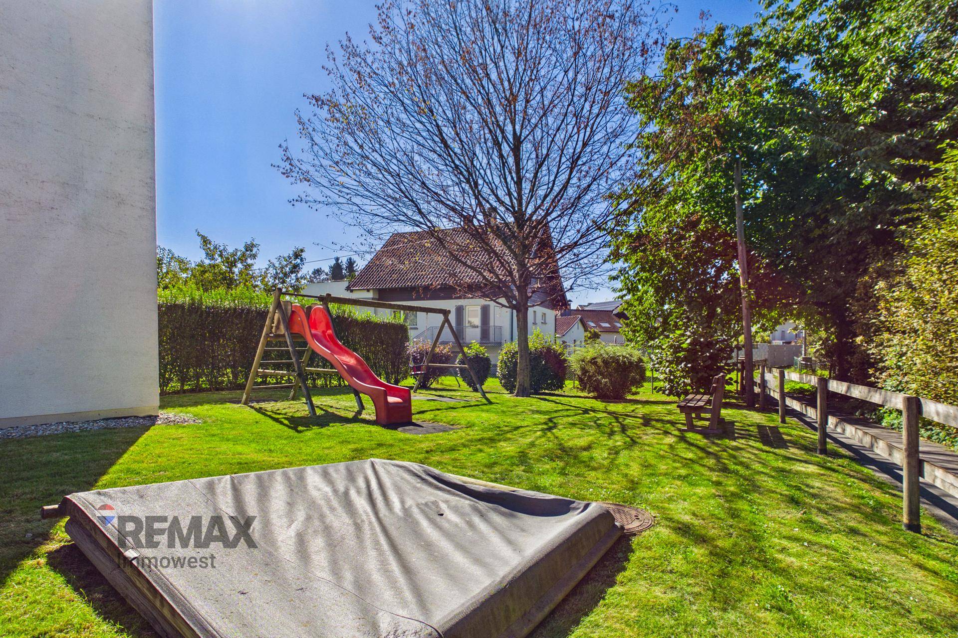 Gemeinschaftlicher Gartenbereich mit Spielplatz, Rutsche und Schaukeln für Kinder.