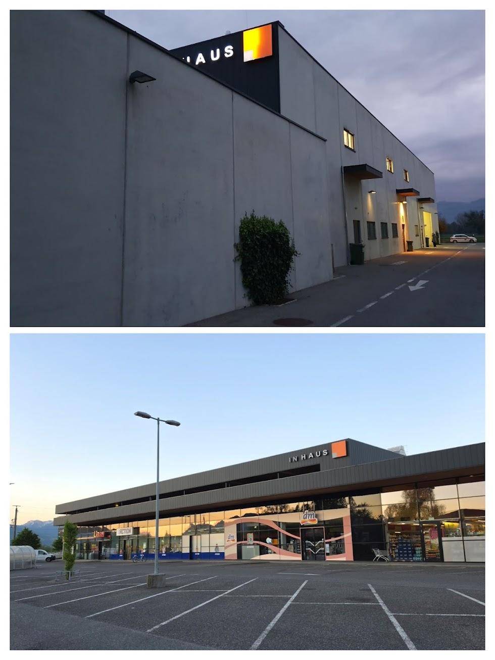 Modernes Geschäftsgebäude mit großer Glasfassade und weitläufigem Parkplatz unter einem bewölkten Himmel.