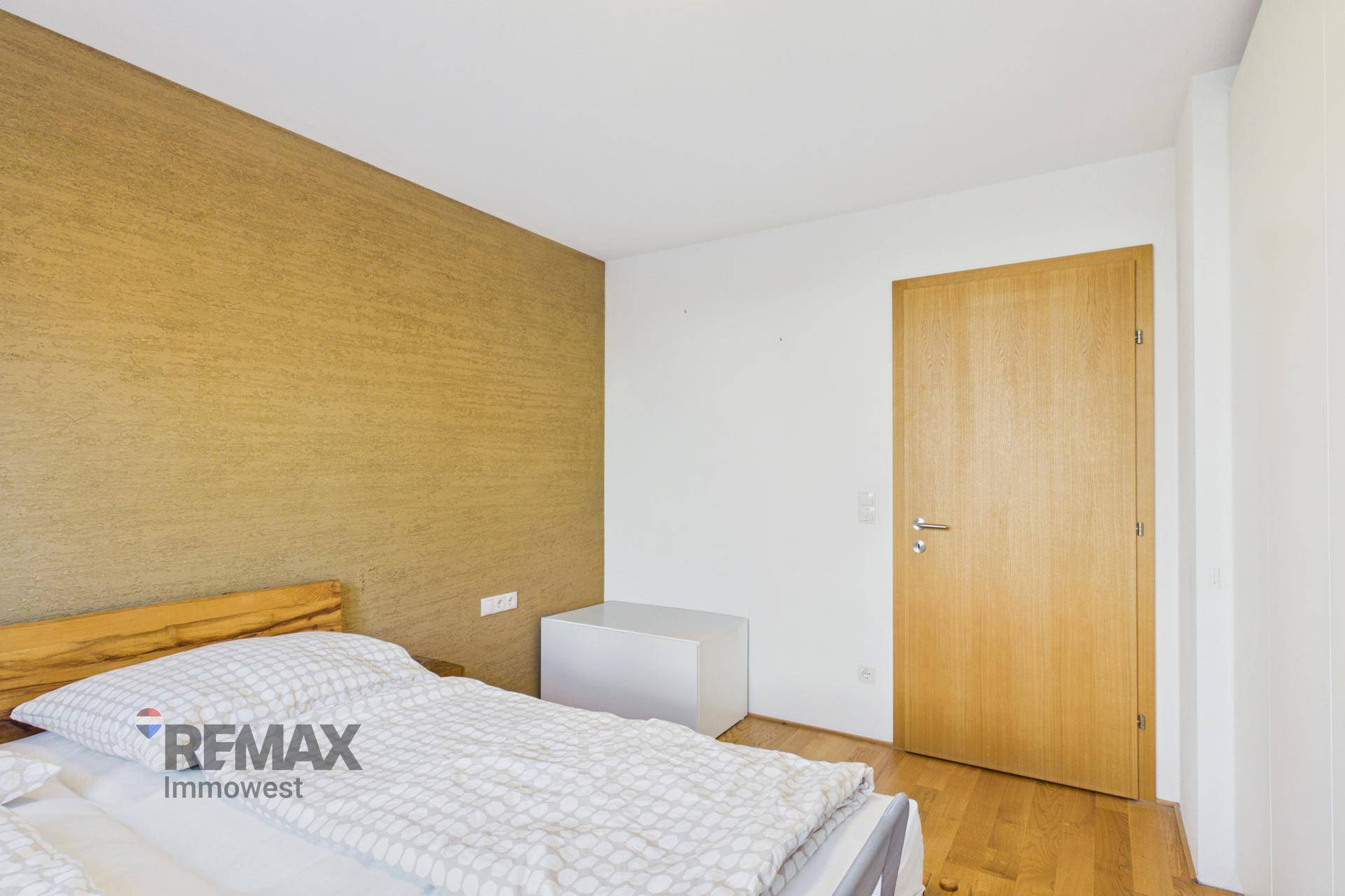 Schlafzimmer mit Holzbett, Holzboden und einer Holztür.