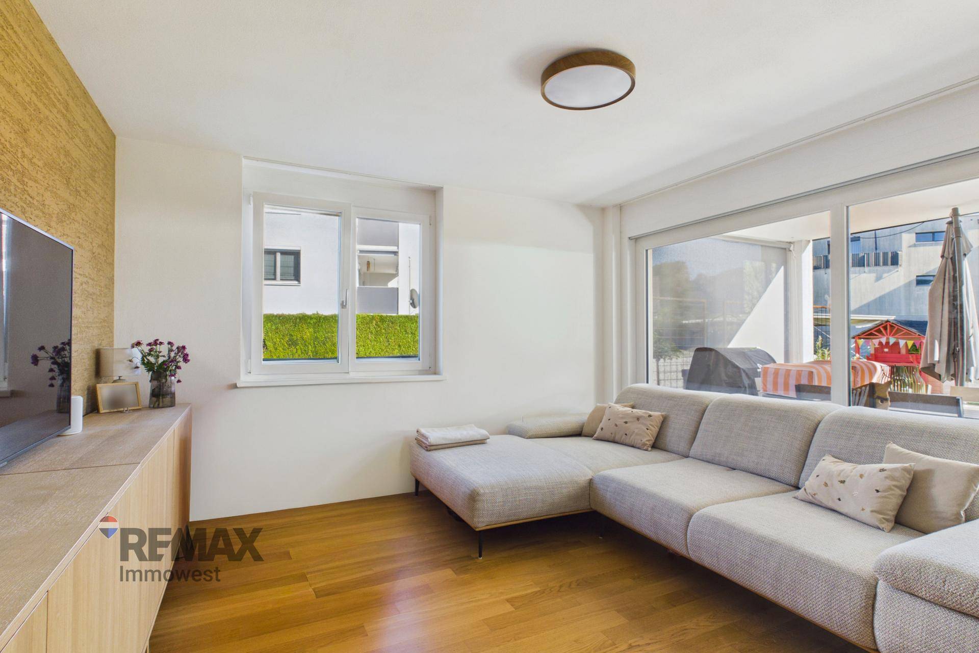 Geräumiges Wohnzimmer mit großem Sofa, Holzboden und Zugang zu einer Terrasse.