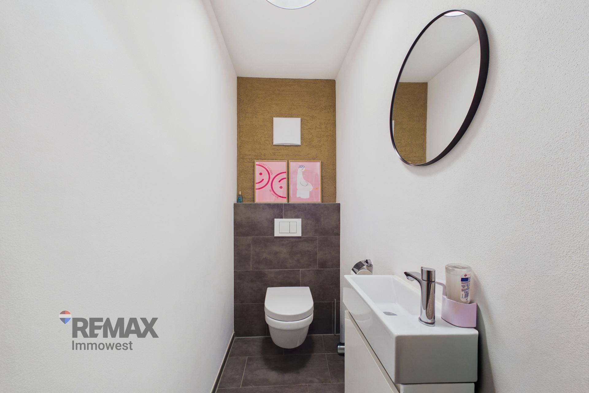 Modernes Gäste-WC mit Wand-WC, Einzelwaschbecken und ovalem Spiegel.