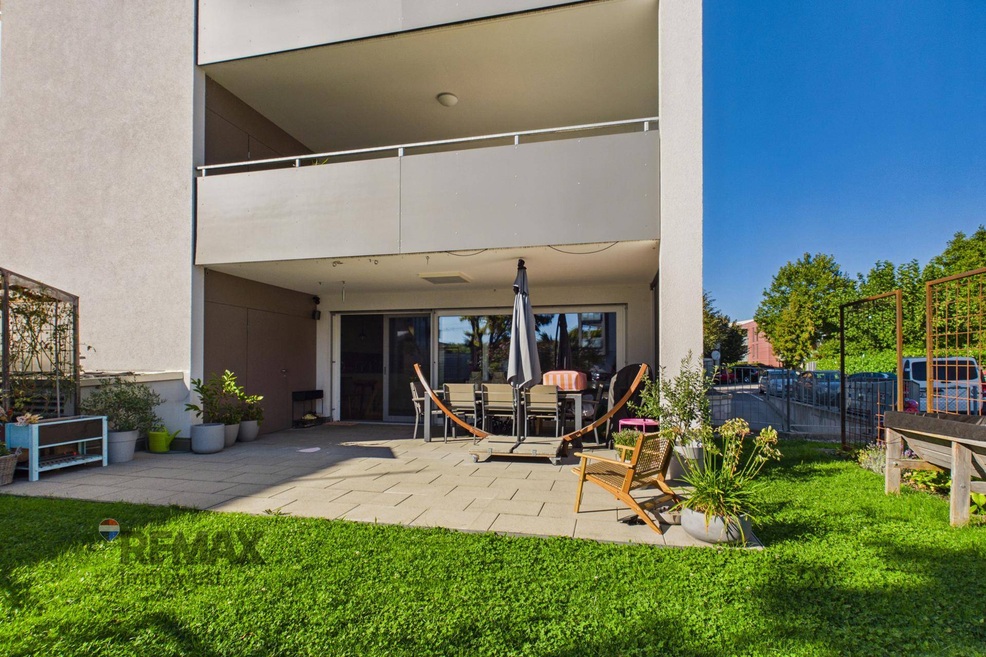 Große gepflasterte Terrasse mit Gartenmöbeln und angrenzender Rasenfläche.