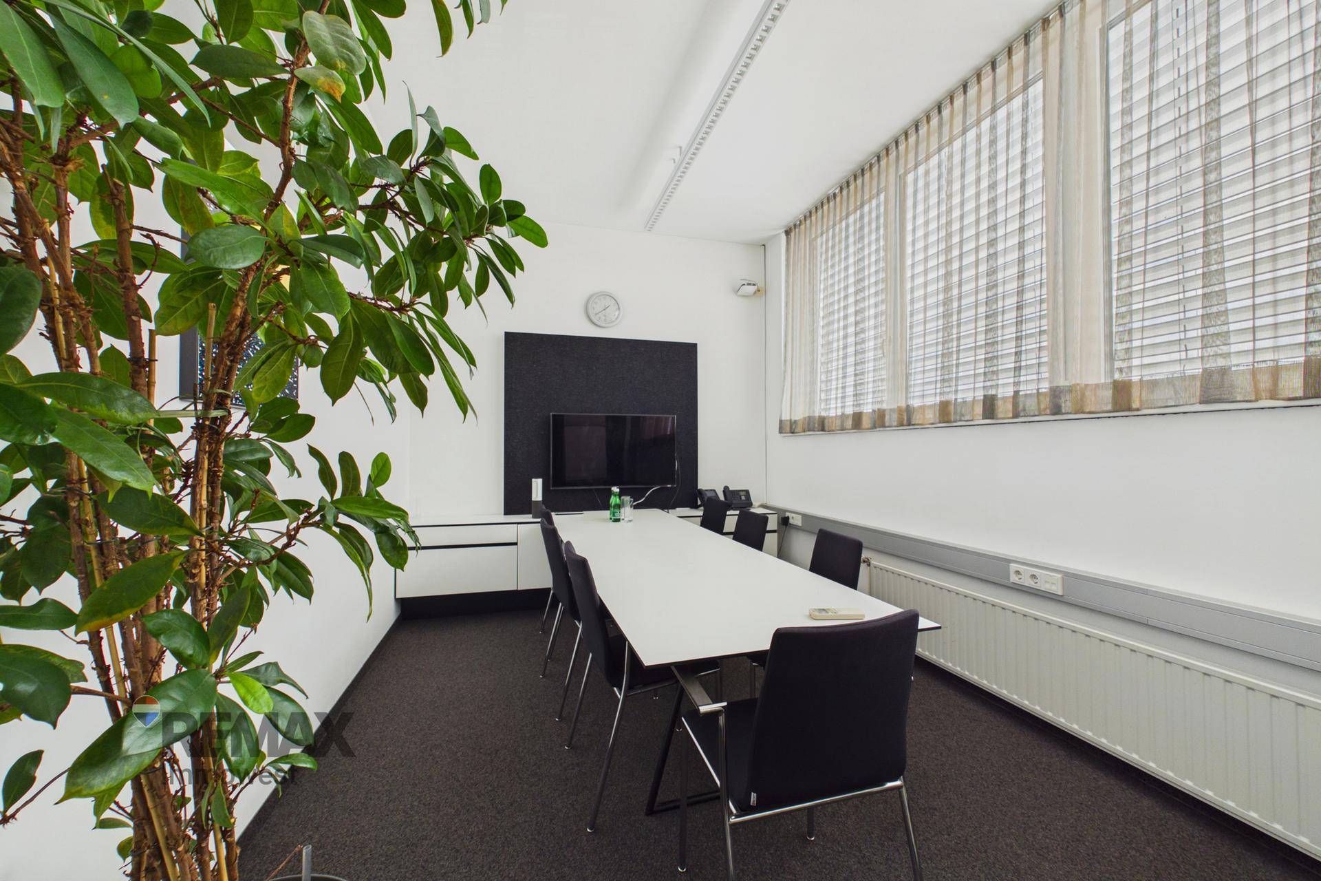 Geräumiger Konferenzraum mit großem Tisch, bequemen Stühlen und einem Flachbildschirm für Besprechungen.