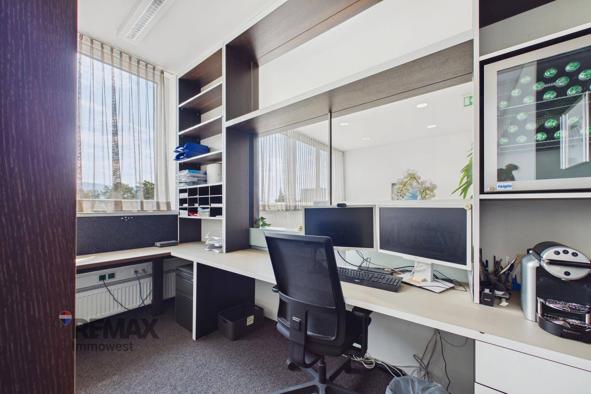 Funktionales Eckbüro mit integrierten Regalen, Arbeitsplatz und einem kleinen Kühlschrank für Getränke.