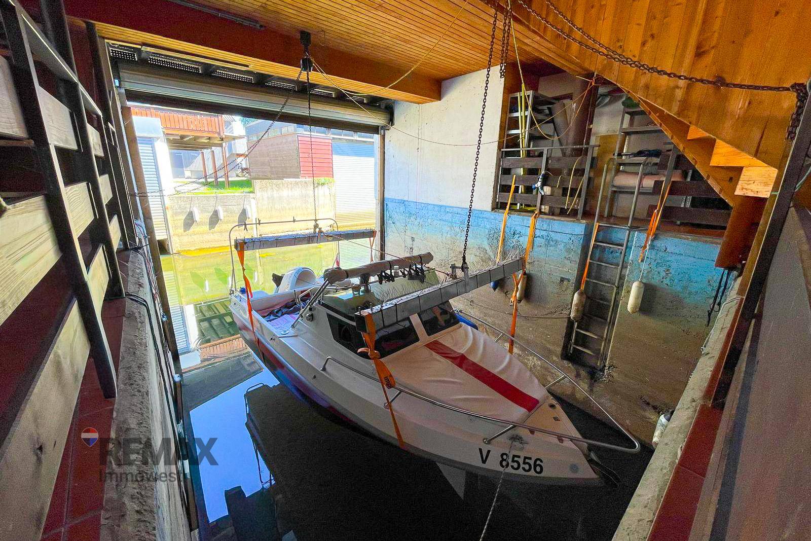 Bootsgarage mit einem Motorboot im Wasser und Holzbalken an der Decke.