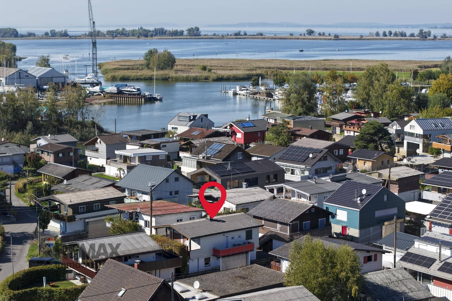 Luftaufnahme der Siedlung mit vielen Häusern, einem See im Hintergrund und einem markierten Grundstück.