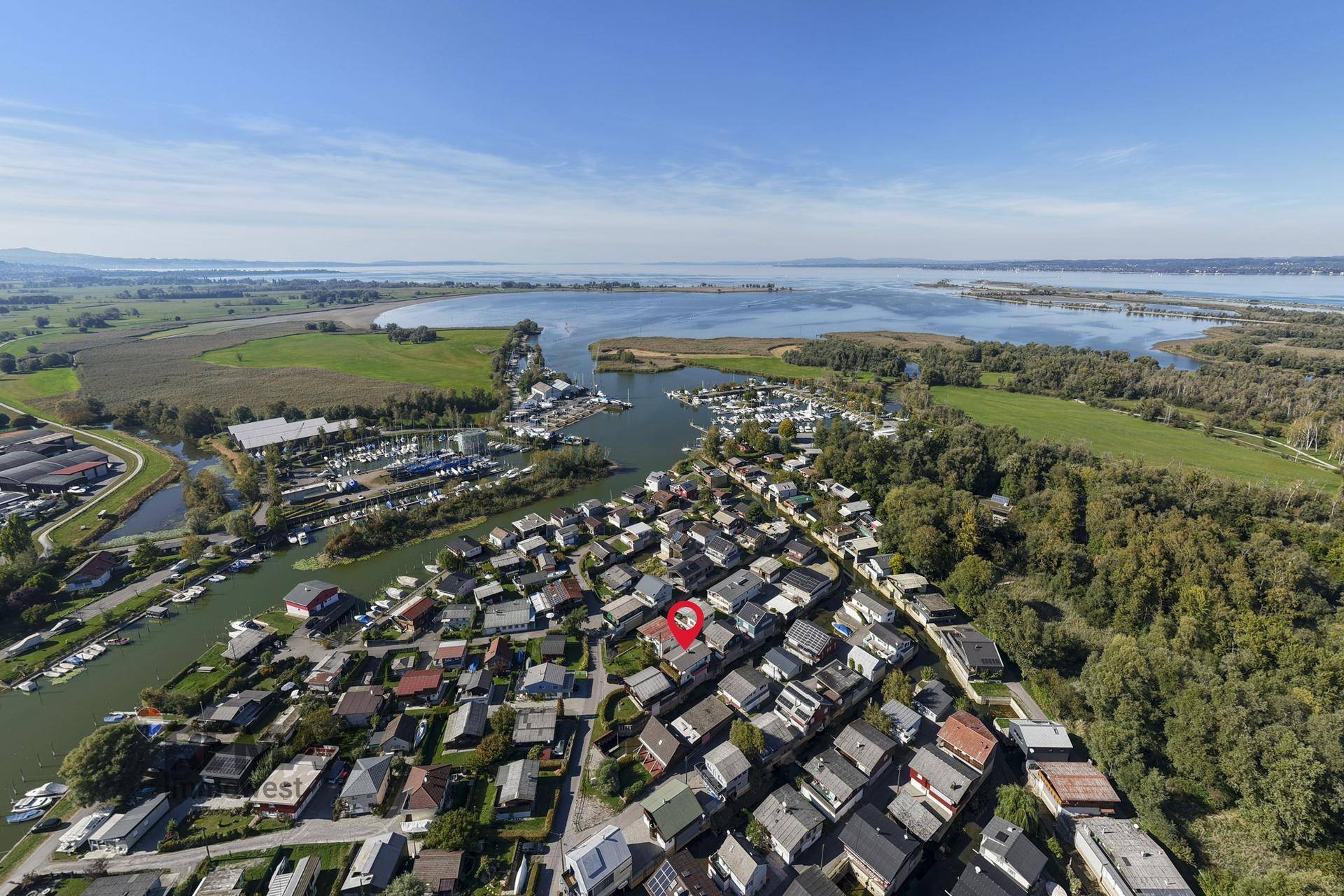 Weitläufige Luftaufnahme der Wohnsiedlung am See mit angrenzenden Feldern und Wäldern.