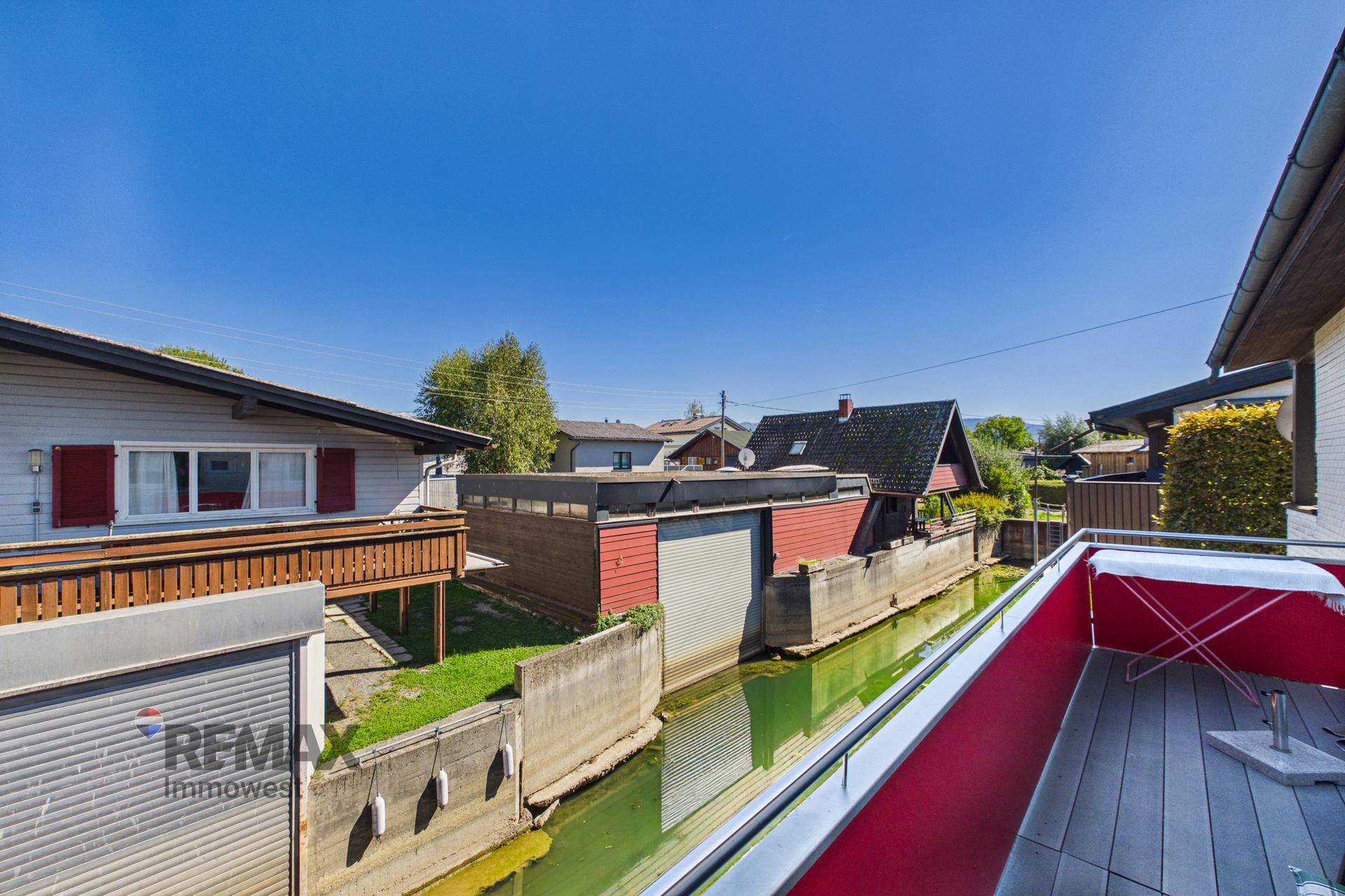 Balkon mit rotem Geländer und Blick auf den Kanal sowie weitere Gebäude.
