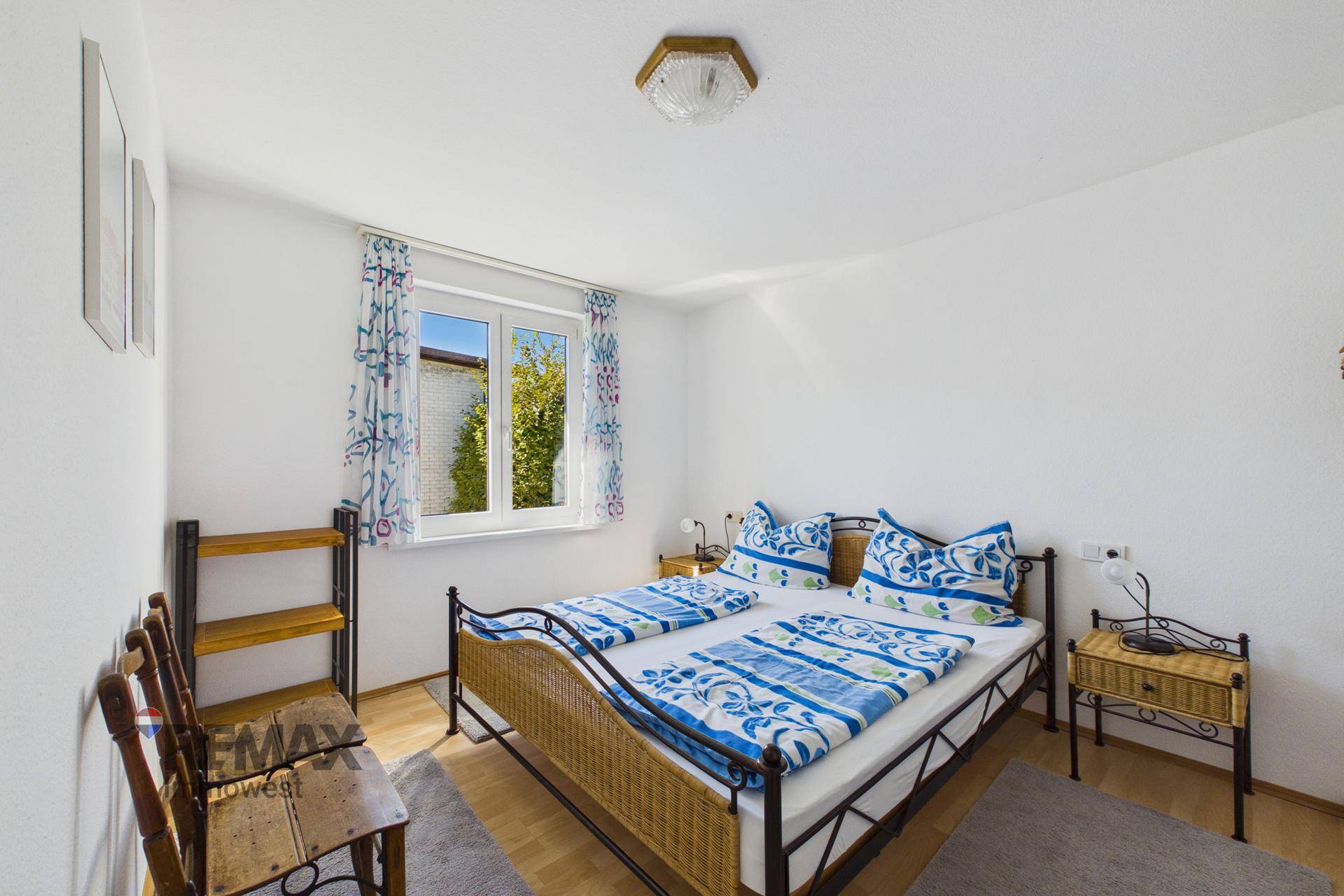 Schlafzimmer mit Doppelbett, hellen Wänden und einem Fenster mit Blick ins Grüne.