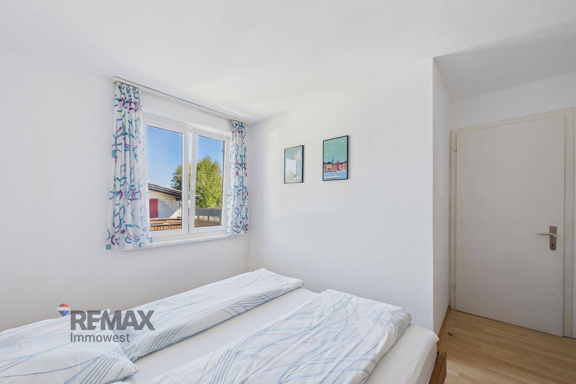 Helles Schlafzimmer mit Doppelbett und Fenster, das viel Tageslicht hereinlässt.