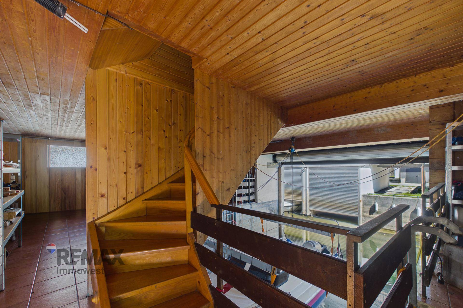 Holztreppe führt von einem Flur hinunter zur Bootsgarage mit Blick auf den Kanal.