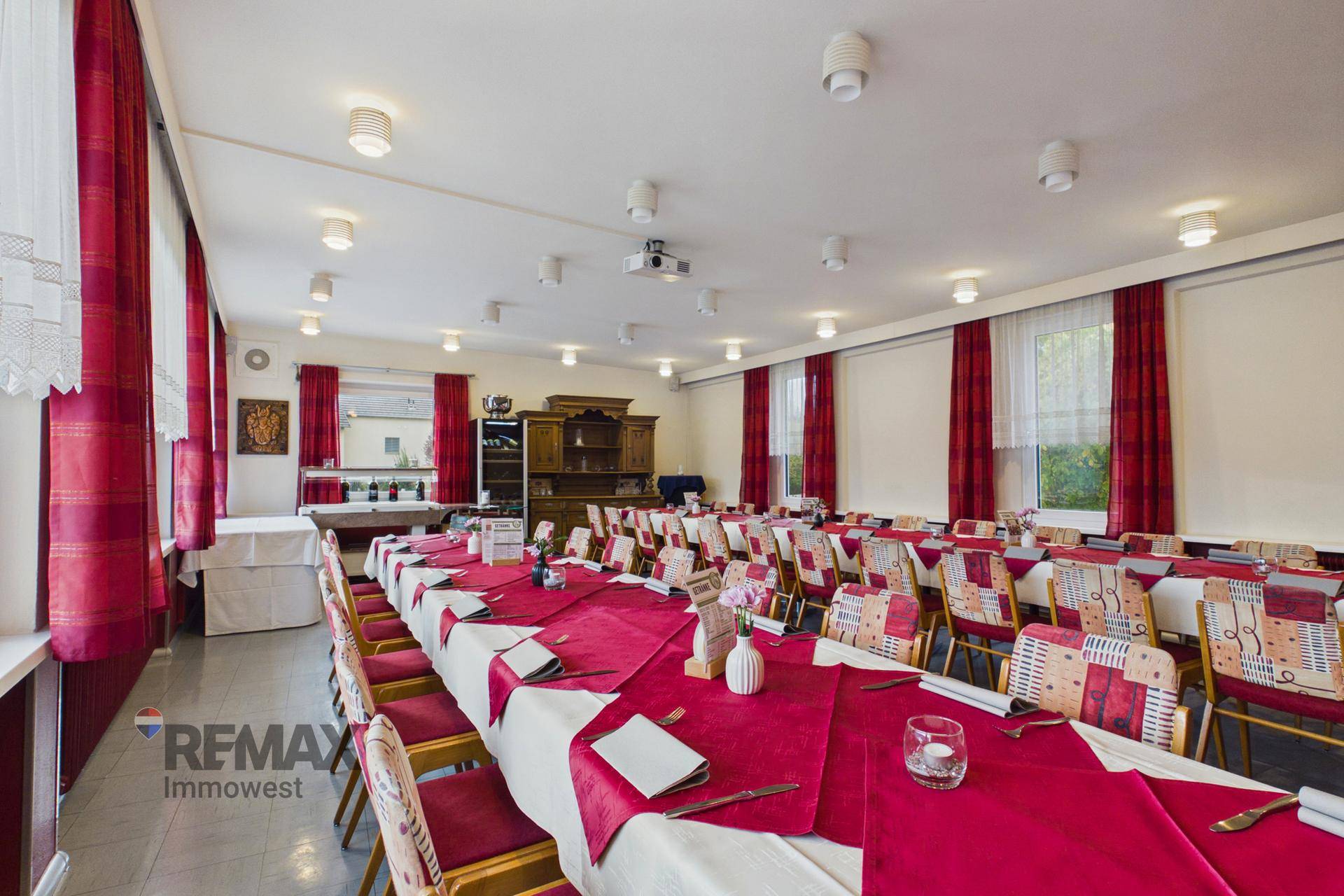 Langer Speisesaal mit traditionellen Holzmöbeln, roten Akzenten und vielen Sitzgelegenheiten.