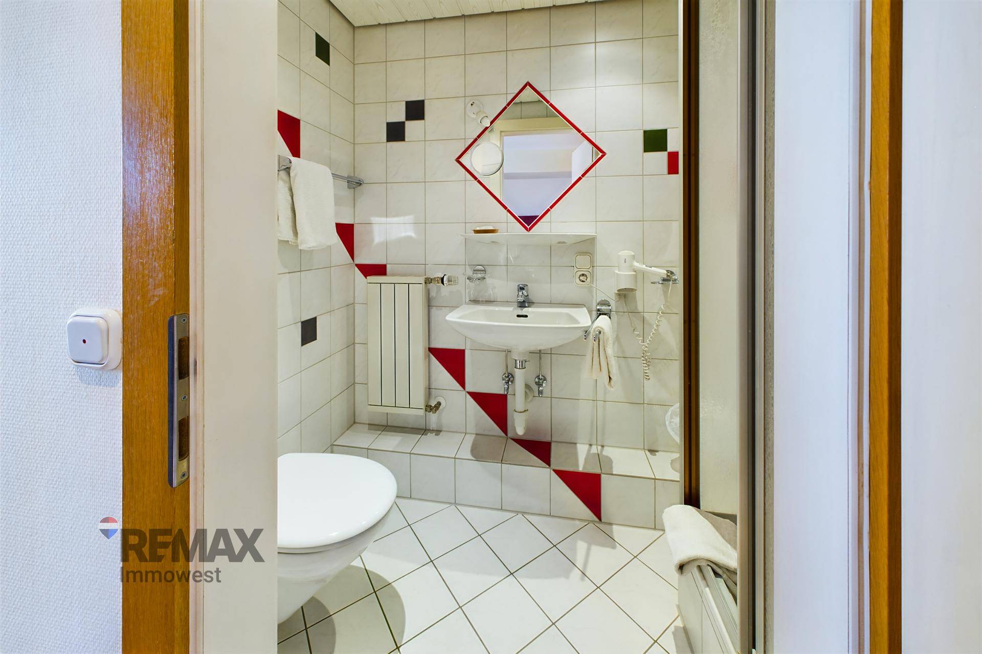 Badezimmer mit WC, Waschbecken und farbigen Fliesen in einem verspielten Muster.