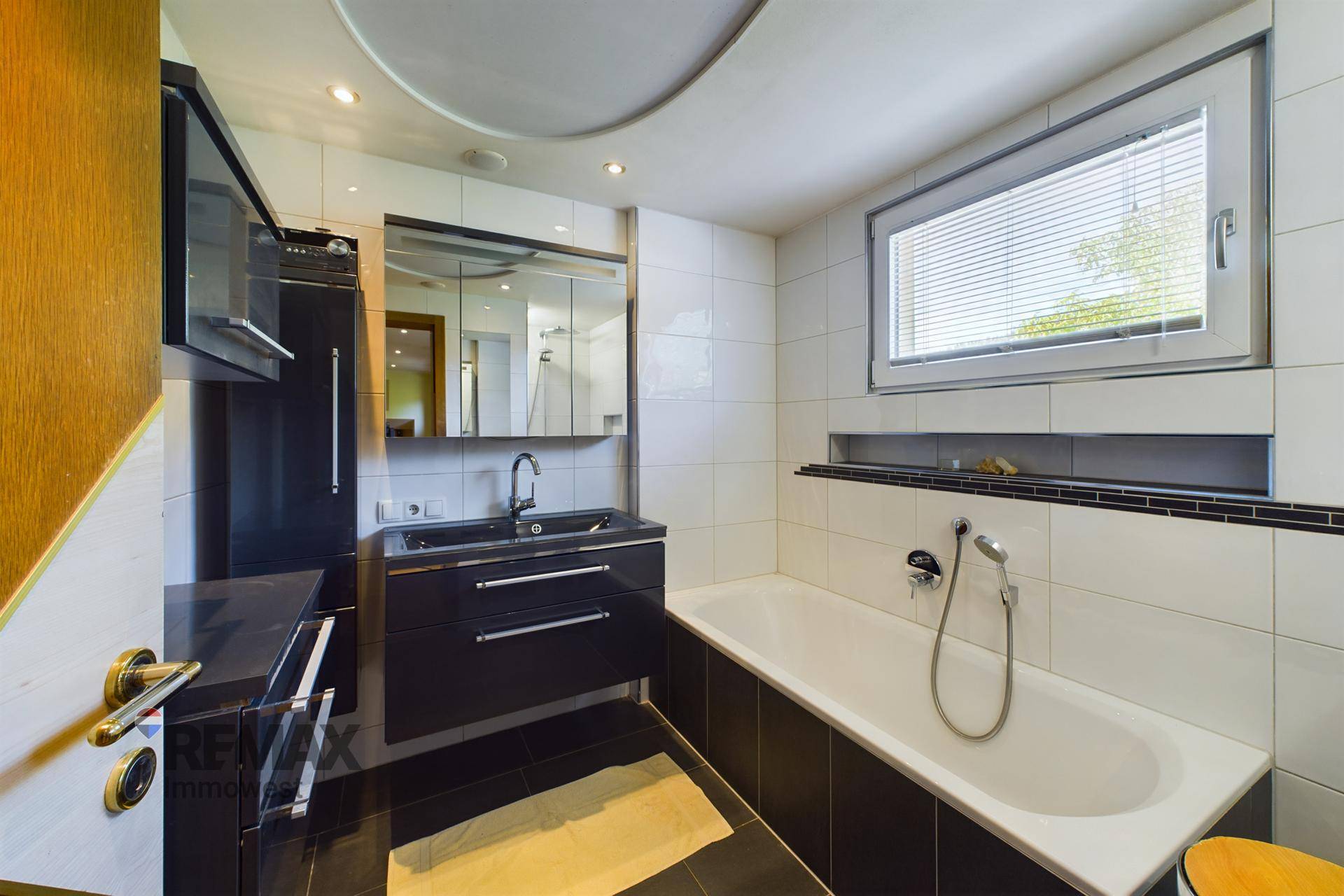 Badezimmer mit Badewanne, modernem Waschtisch und schwarz-weißen Fliesen.