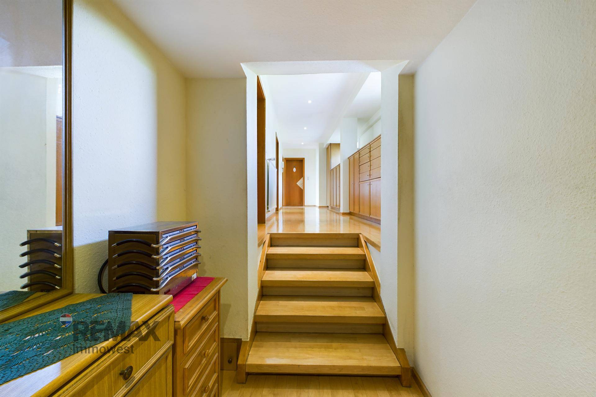 Heller Flur mit Holztreppe und Holzboden, der zu weiteren Räumen führt.