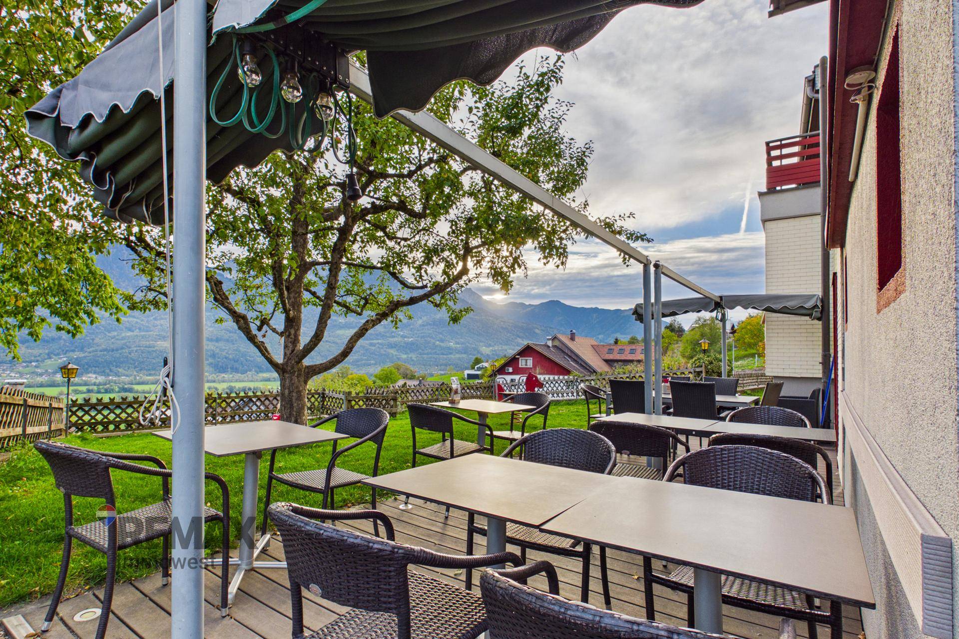 Terrasse mit Sitzgelegenheiten und weitem Blick über das Tal und die Berge.