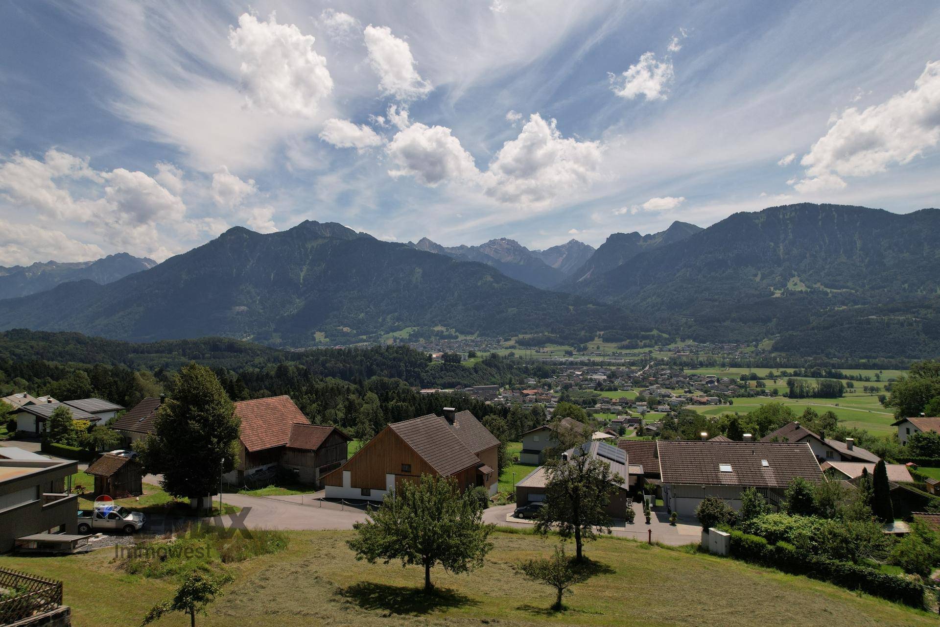 Panoramablick auf die umliegende Dorflandschaft und die majestätischen Berge im Hintergrund.