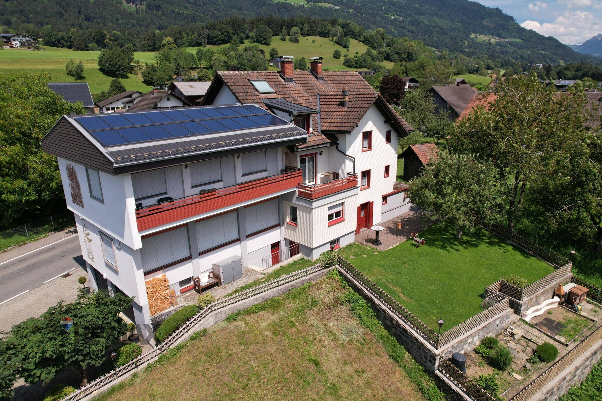 Luftaufnahme des Anwesens mit Gebäude, Garten und Photovoltaikanlage auf dem Dach.