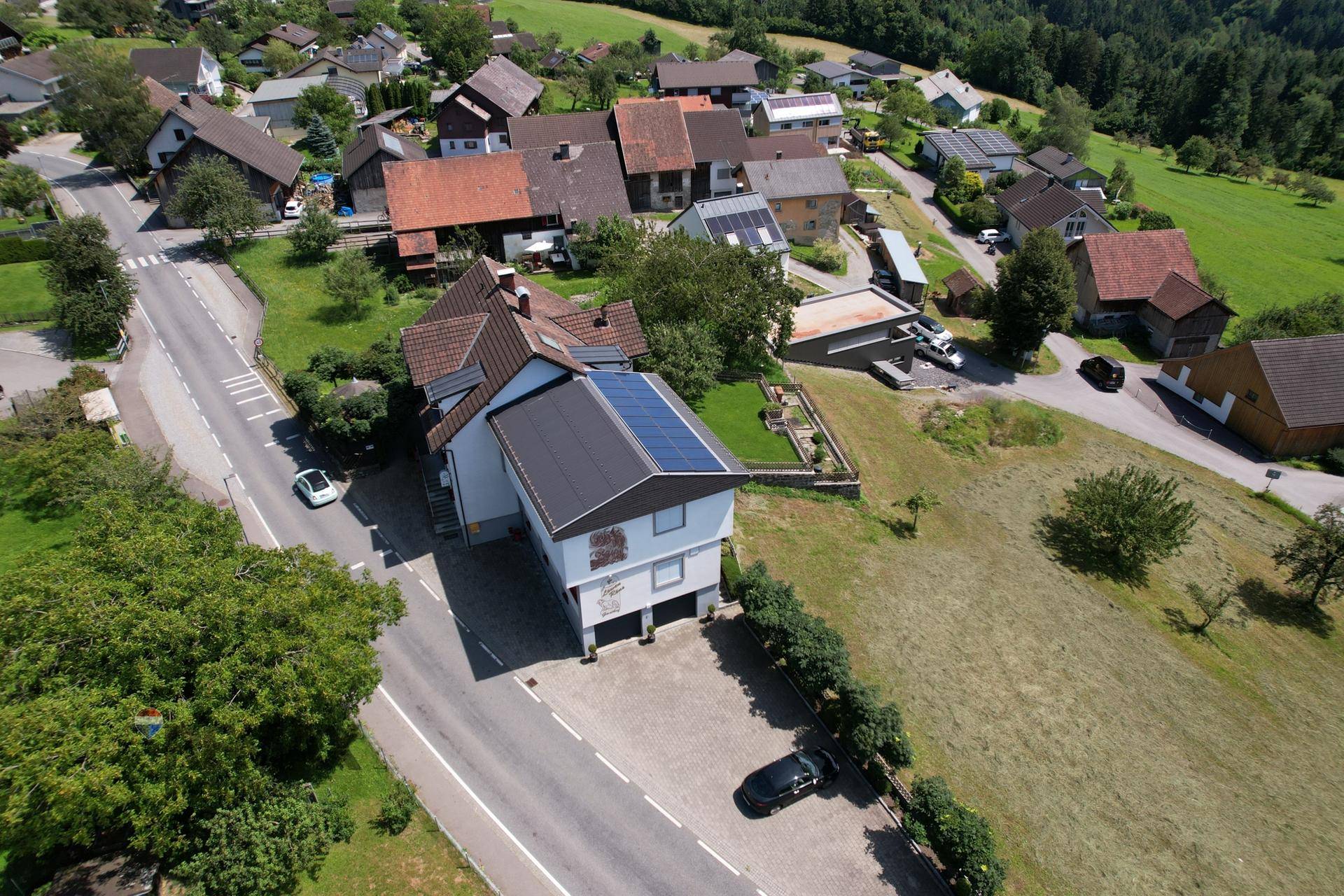 Luftaufnahme des Anwesens und der Umgebung mit Straße und benachbarten Häusern.