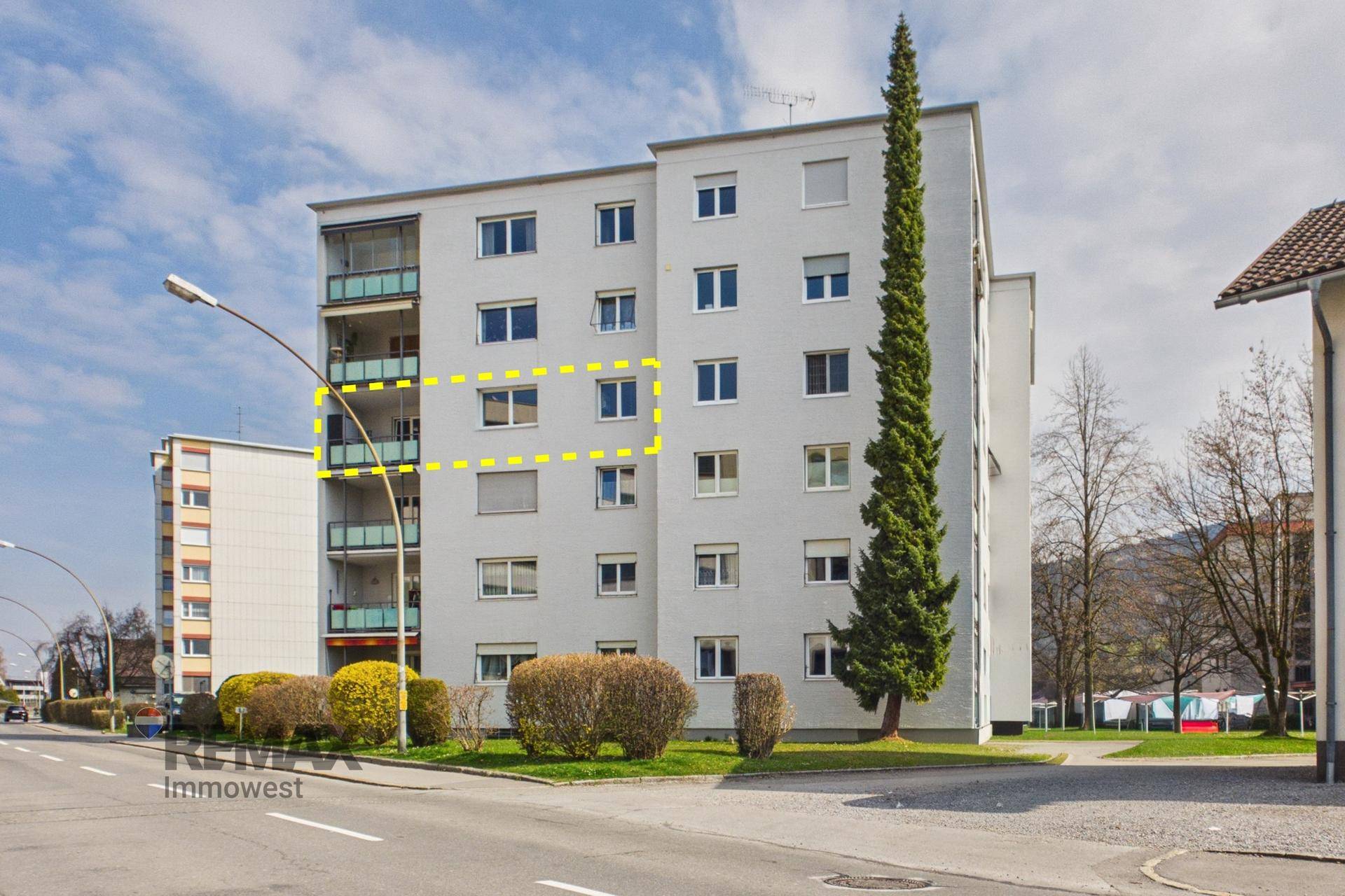 Ansicht eines Mehrfamilienhauses mit Balkonen und einer hervorgehobenen Wohneinheit.