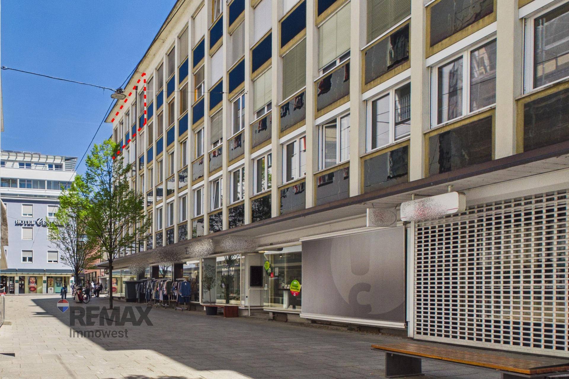 Fassade eines Geschäftsgebäudes mit vielen Fenstern und einem Vordach über dem Gehweg.