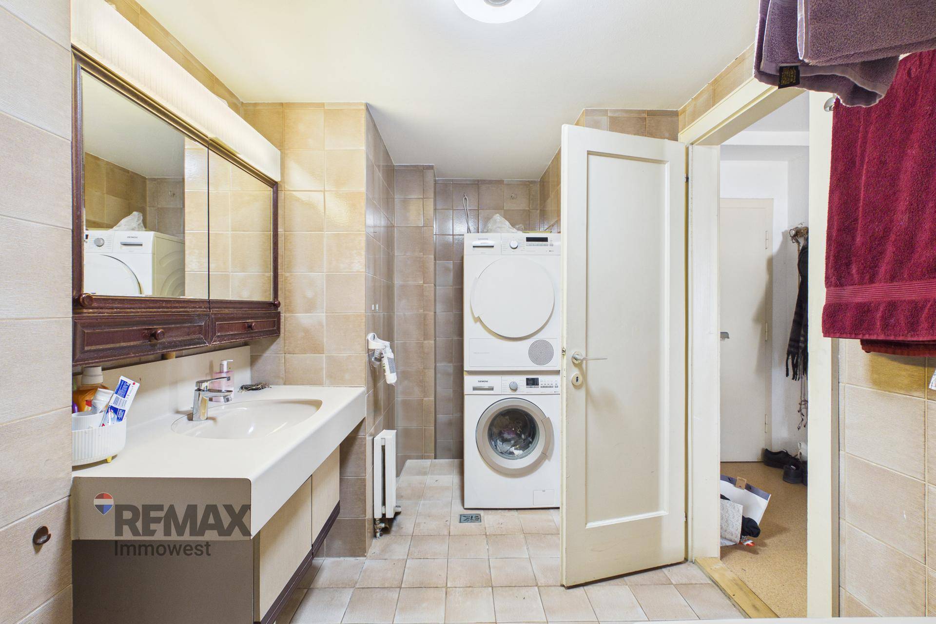 Badezimmer mit Waschbecken, Spiegelschrank und gestapelter Waschmaschine und Trockner.