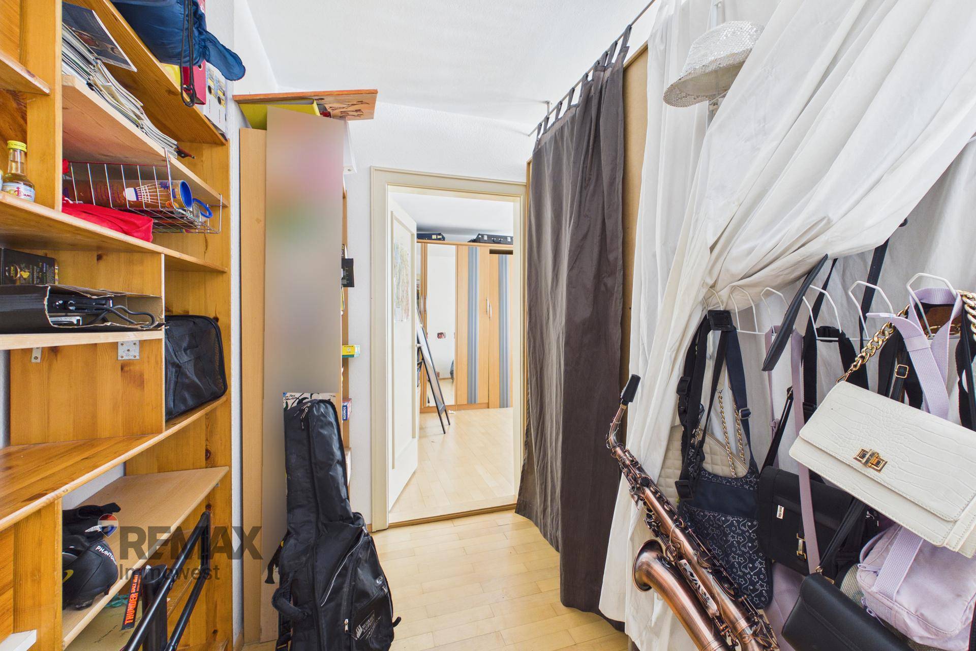 Begehbarer Kleiderschrank oder Abstellraum mit Regalen und Vorhängen.