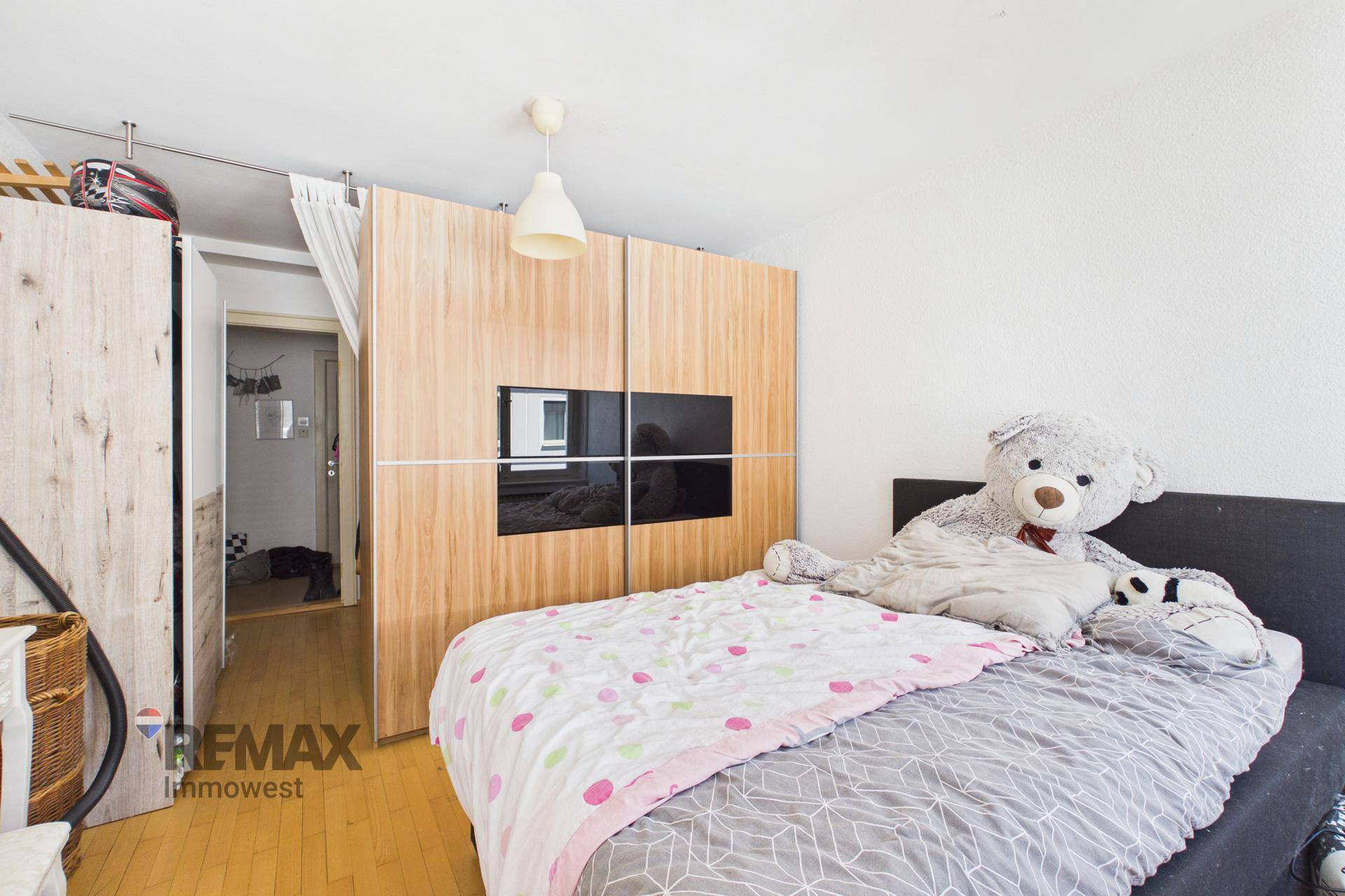Schlafzimmer mit Doppelbett, großem Schrank und Holzboden.