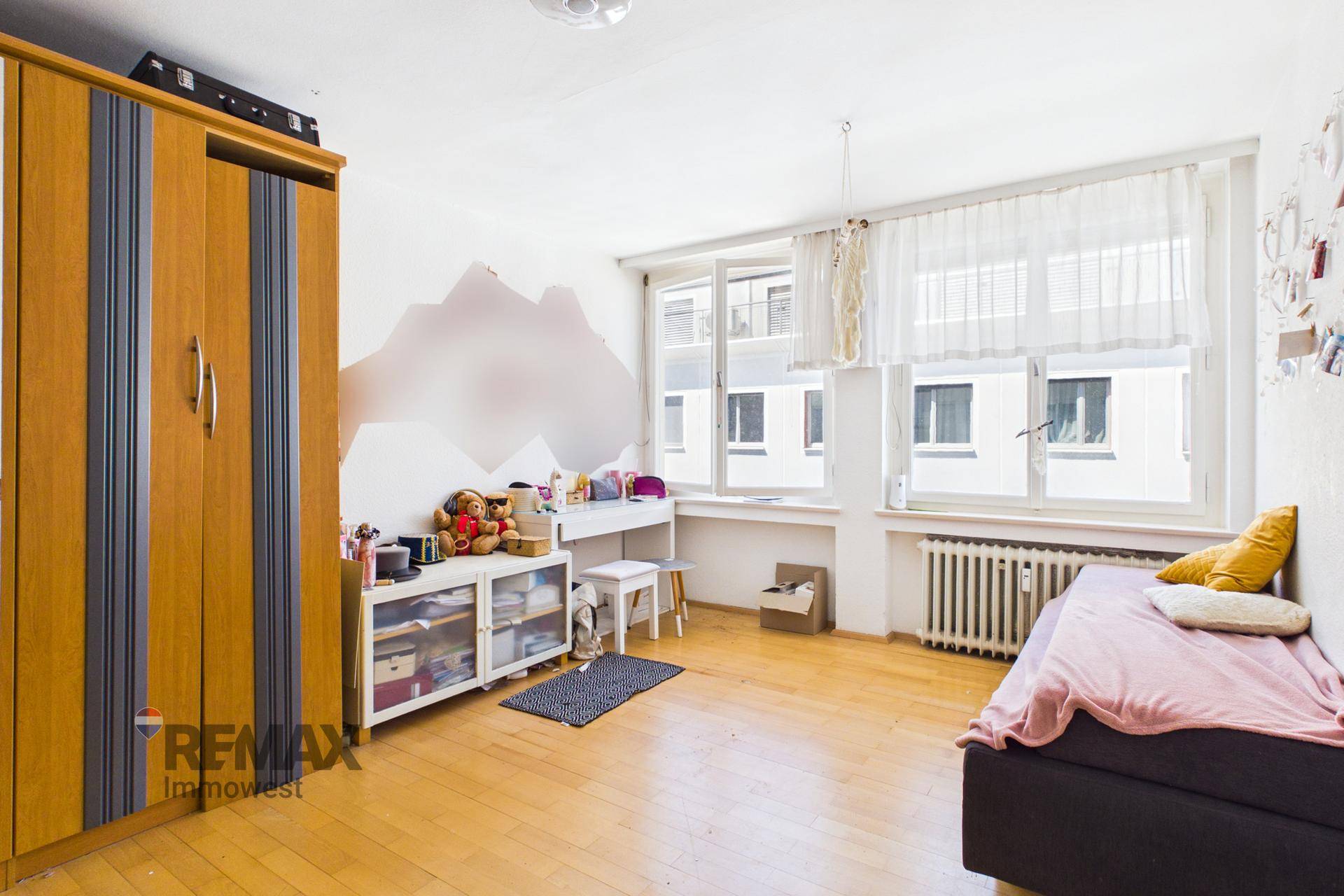 Kinderzimmer mit Schrank, Schreibtisch und großem Fenster, hell und freundlich.
