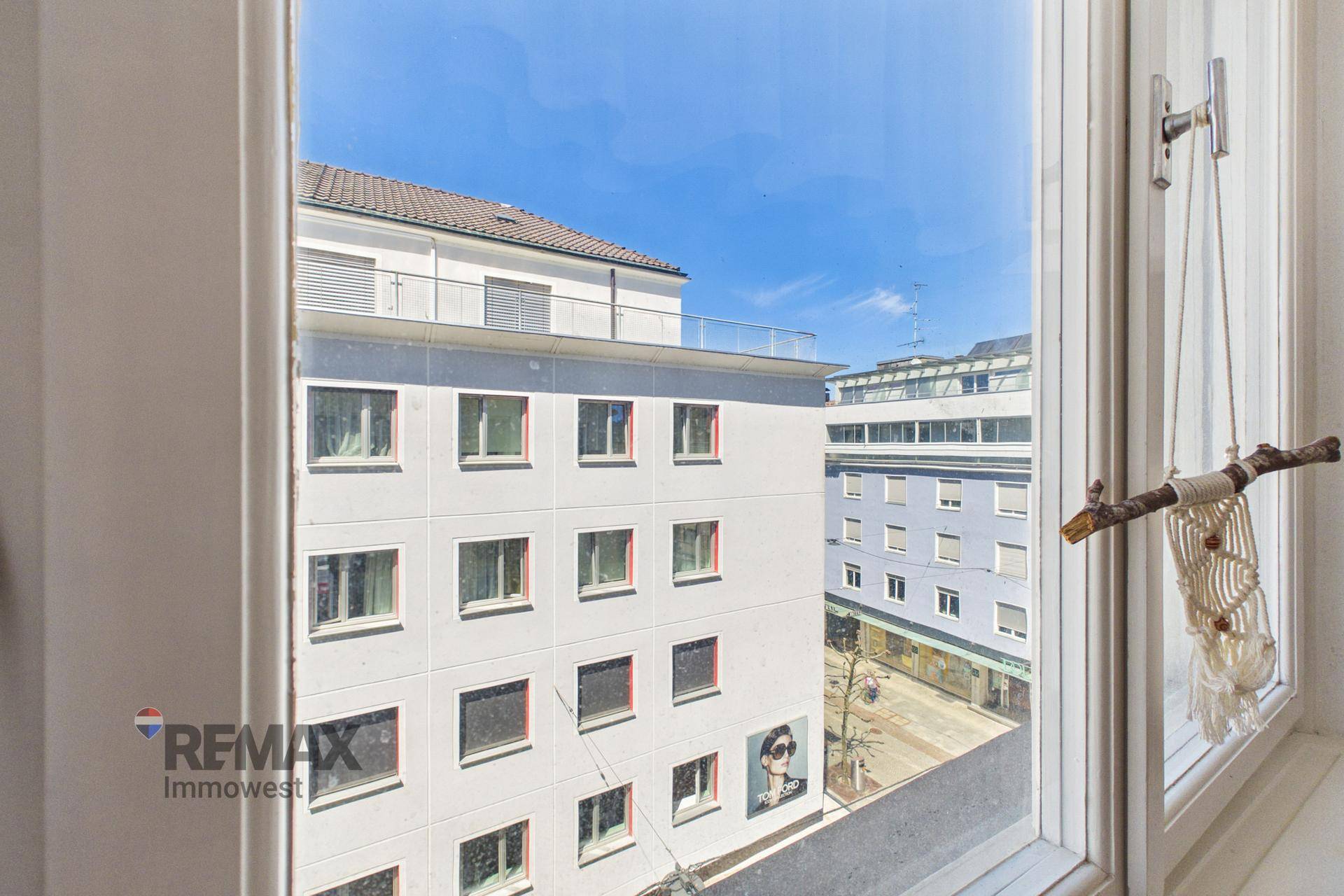 Blick aus dem Fenster auf die umliegenden Gebäude und den blauen Himmel.