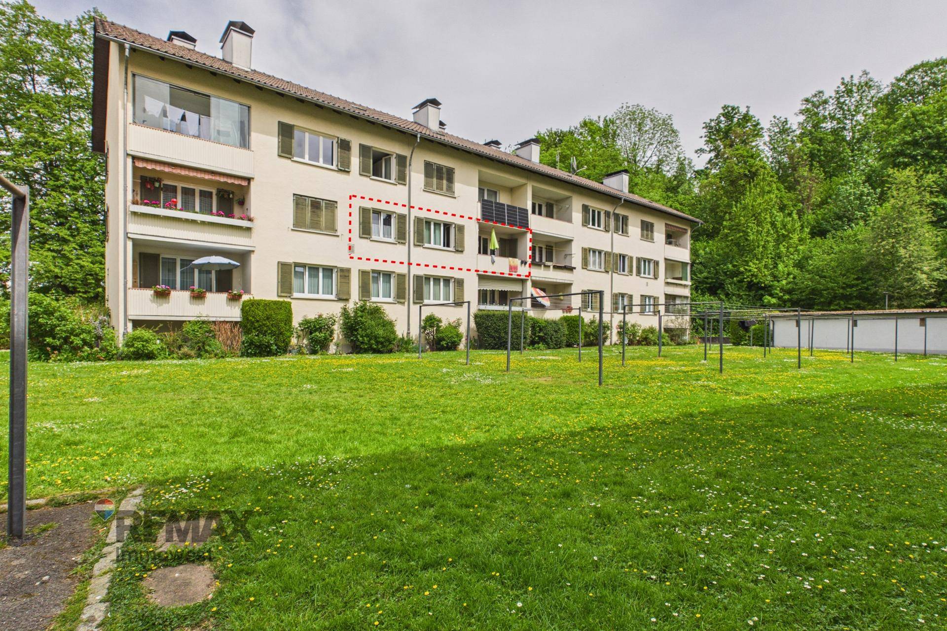 Ansicht des Mehrfamilienhauses von der Seite mit angrenzendem Waldgebiet und Grünfläche.